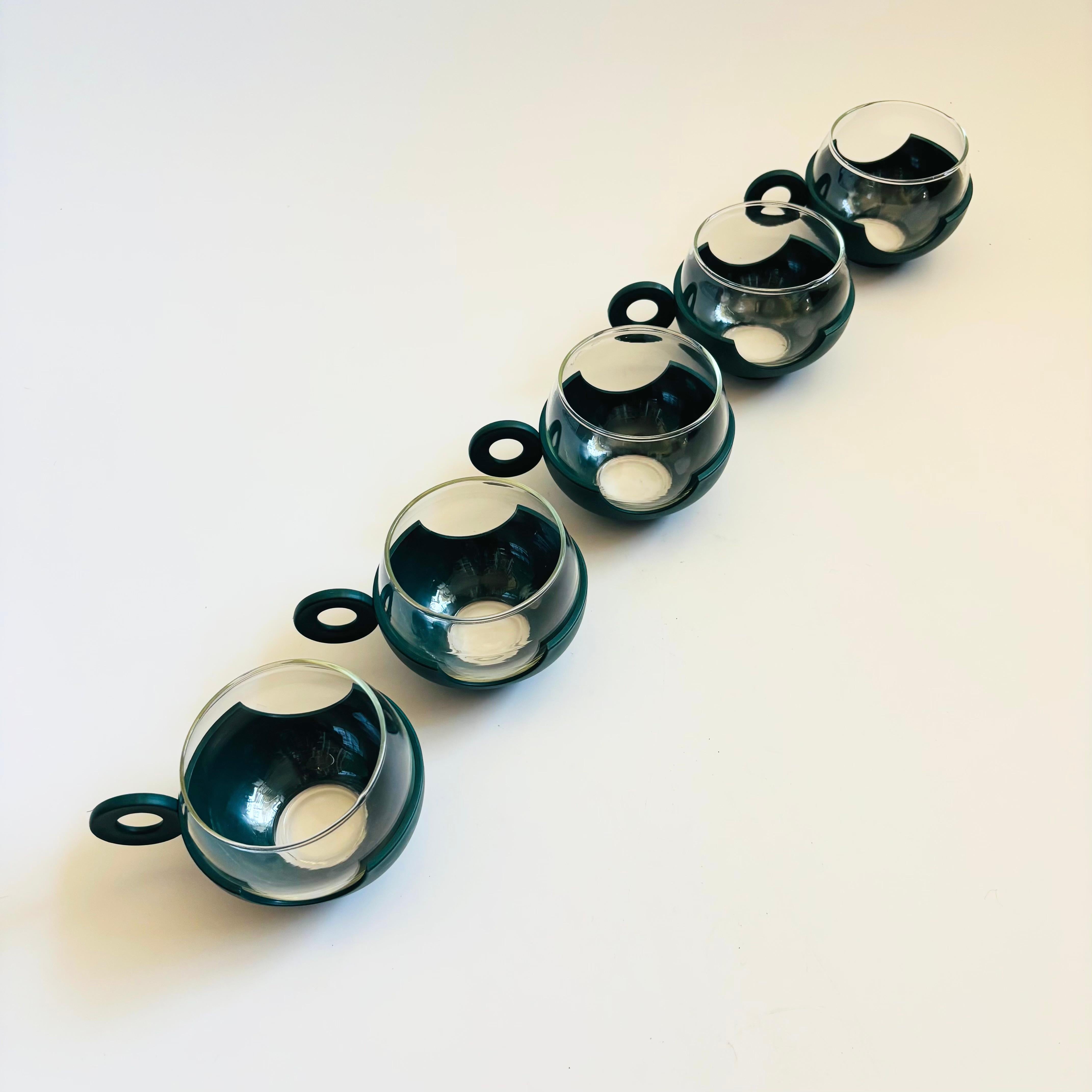 Ein Satz von 5 Bechern aus der Mitte des Jahrhunderts. Sie bestehen aus Glas, das in einen dunkelgrünen Kunststoffsockel einrastet. Großartiges Design aus der Mitte des Jahrhunderts, bei dem die Sockel wie Untersetzer wirken, um Oberflächen zu