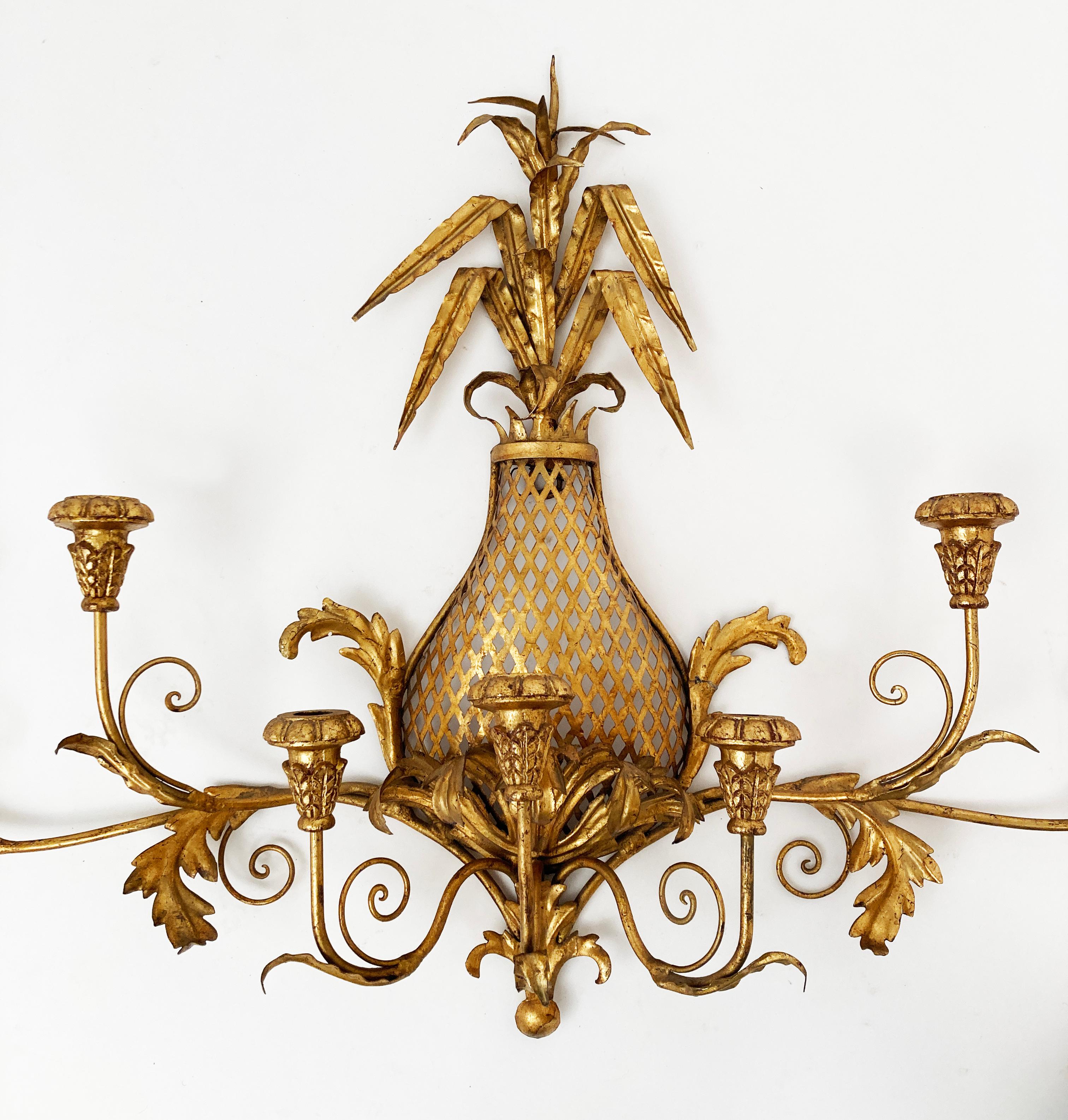 This Hollywood Regency 7-candleholder and pineapple wall sconce is reminiscent of mid 20th century Hollywood when everything was golden! The design of this piece is a perfect balance of ornate leaf work and beautiful French era scroll work that