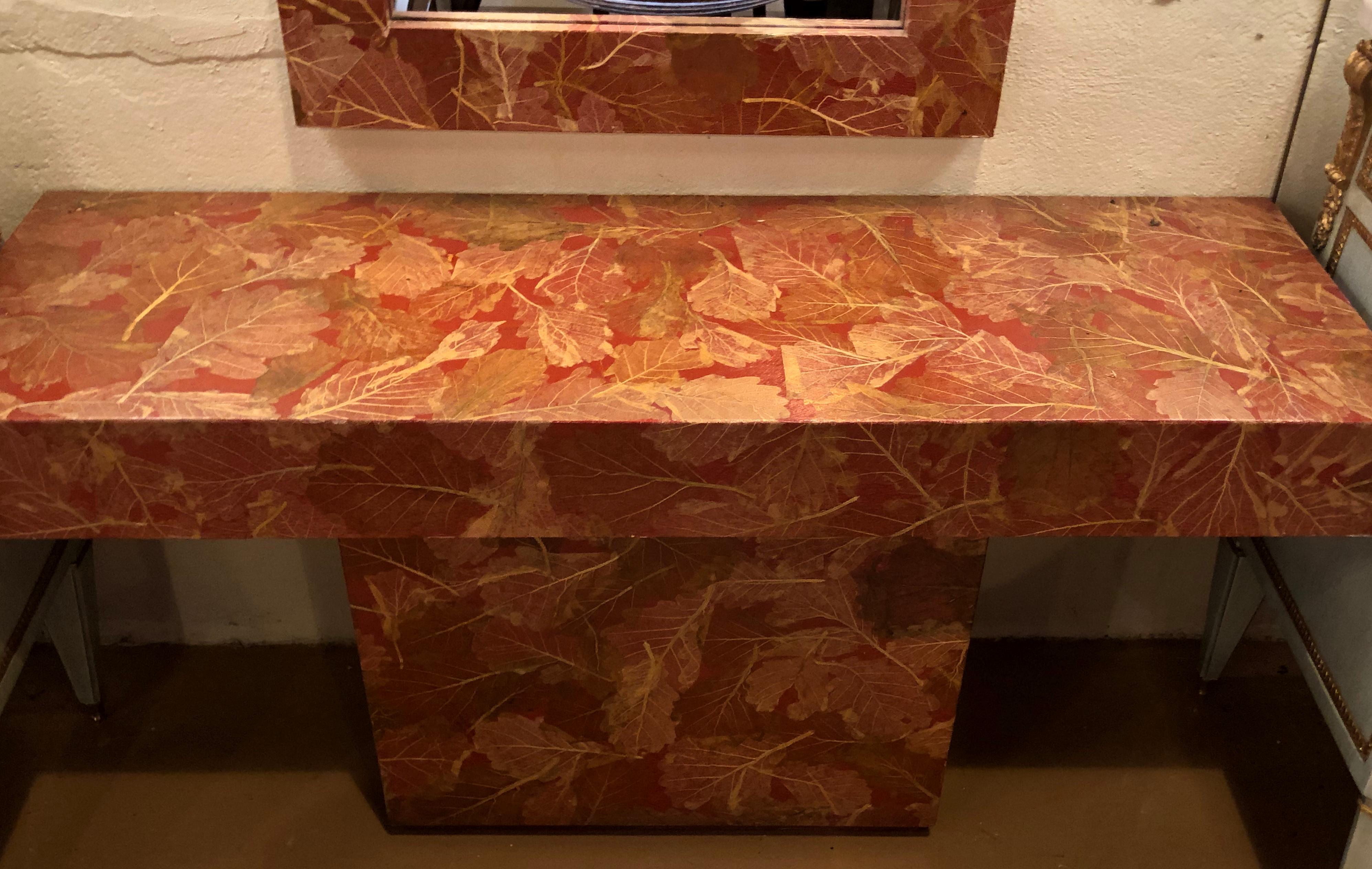 Rose and gold leave design decoupage painted console / vanity with matching mirror. This lovely set has a beautiful salmon and gold color throughout depicting flowing leaves and vine design.
The mirror measures 28 inches height, 49.5 width, and
