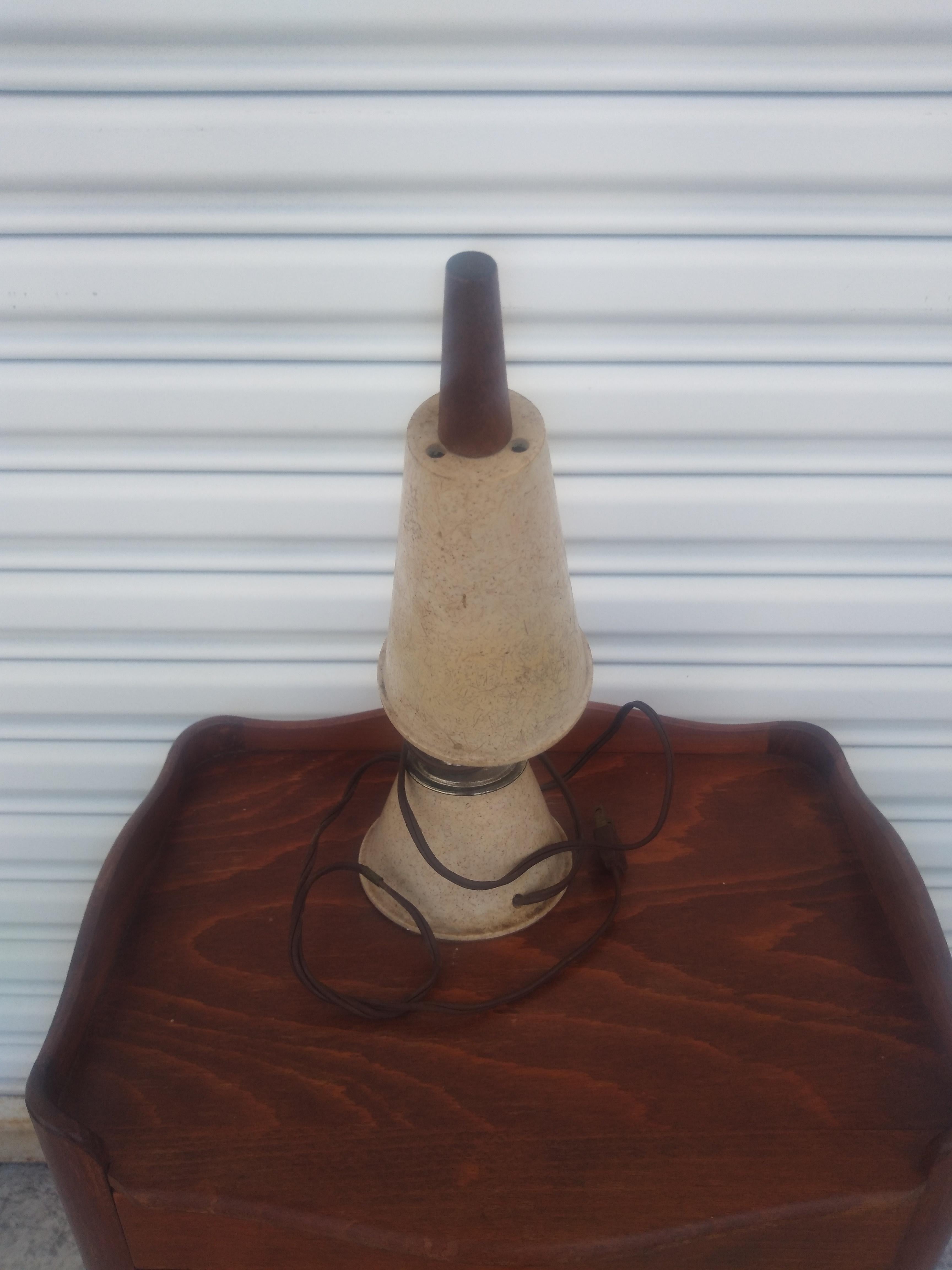 Se trata de una lámpara de sobremesa de cuello de cisne. La base y la pantalla tienen un aspecto de fibra de vidrio sintética. La pantalla tiene un remate de teca. El cuello de cisne hace que sea ajustable.