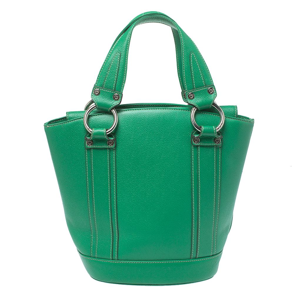 This wonderful MCM design is made from leather and enhanced with silver-tone hardware. The bag has a bucket shape with a flap closure that secures the fabric interior. It is complete with two top handles. Green in shade, it is an apt accessory to