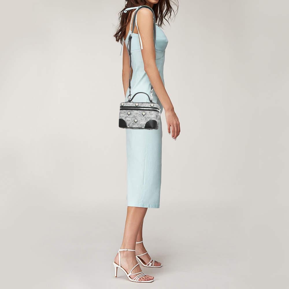 The MCM vanity bag exudes timeless elegance. Crafted with precision, its durable jacquard fabric features the iconic MCM monogram in a chic grey hue. The spacious interior offers functionality, while the rockstar-inspired design adds a touch of edgy