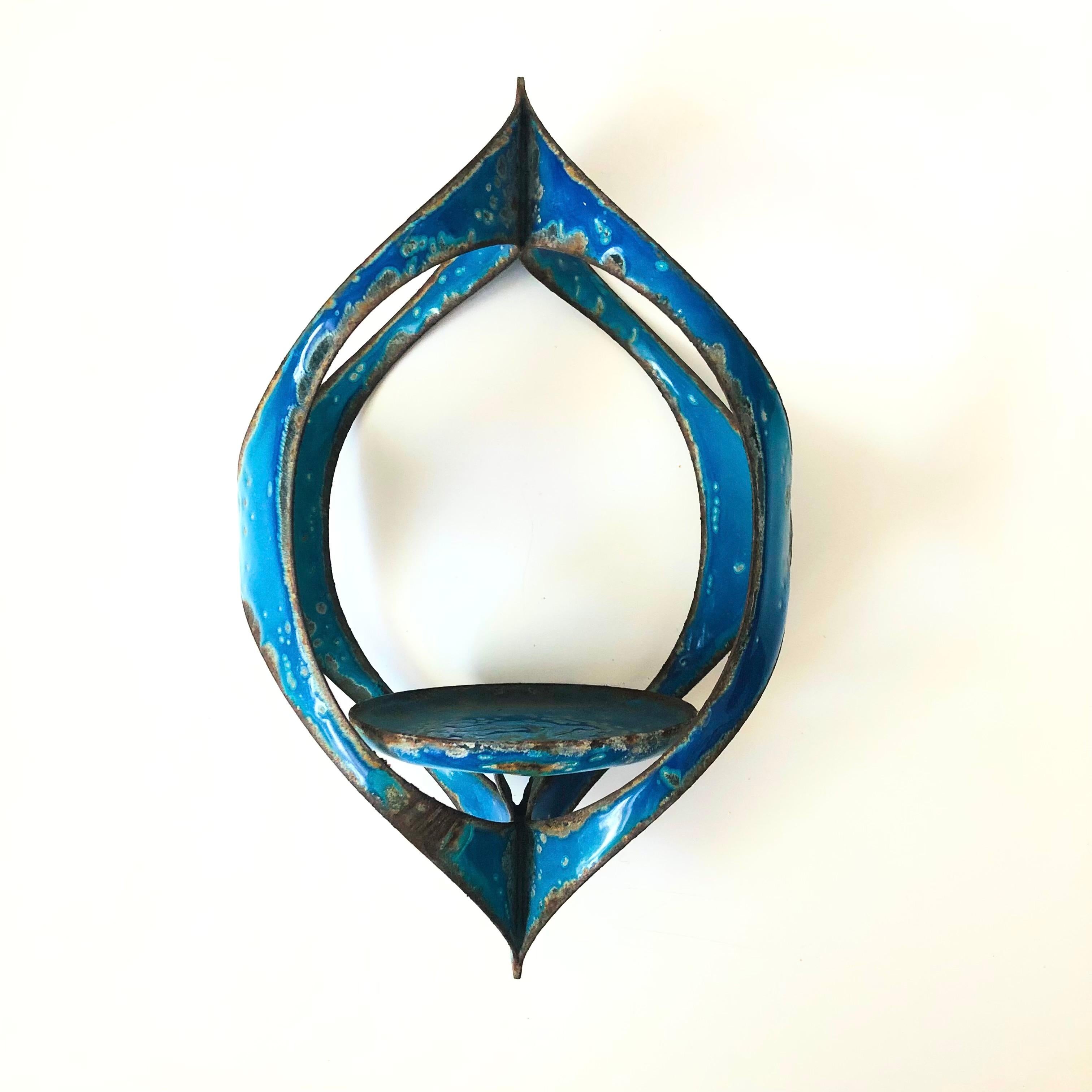 A mid century enameled hanging candle holder, made by Hanova. Vibrant blue color to the enamel. Features a centered circular platform for placing a candle and a hole through the top for hanging.

