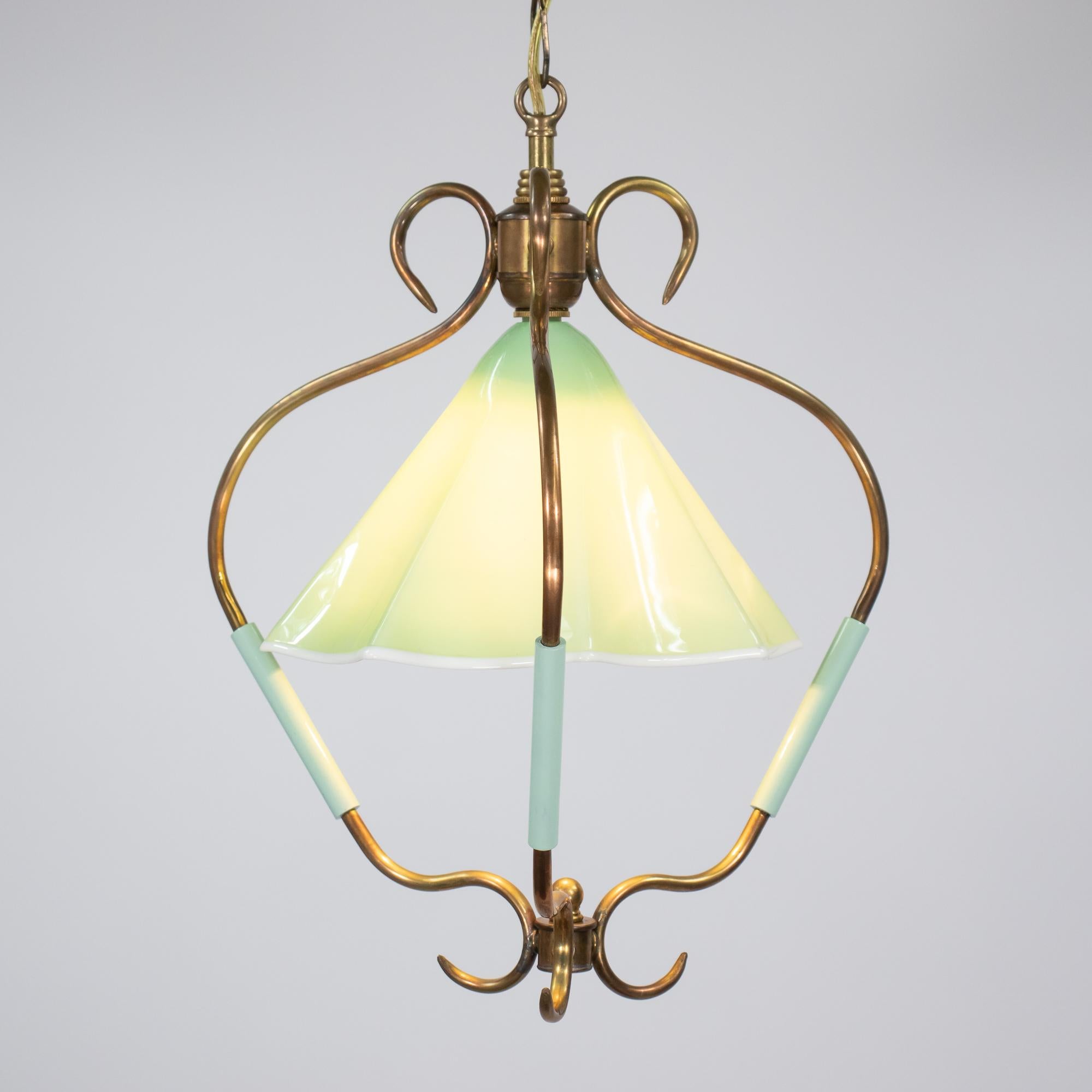 Cette lampe suspendue italienne MCM pr�ésente un cadre sculptural composé de tubes en laiton gracieusement courbés soutenant un abat-jour en verre opalin vert soufflé à la main et bordé de blanc. La forme caractéristique de cloche et la silhouette