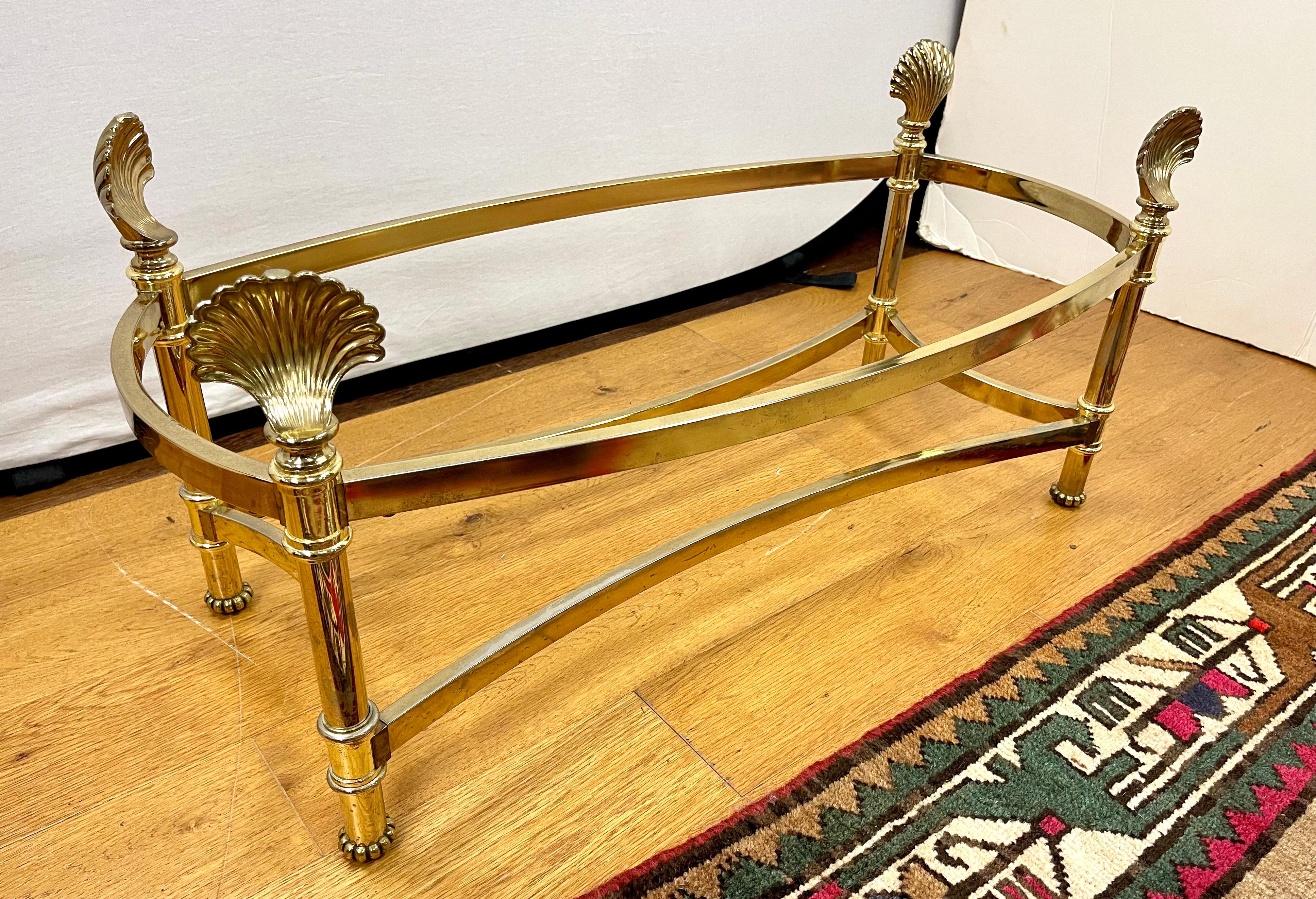 Stunning Mid-Century Modern cocktail table with elegant solid brass bottom with sea shell detail that supports an oval glass top. Belongs in Architectural Digest!