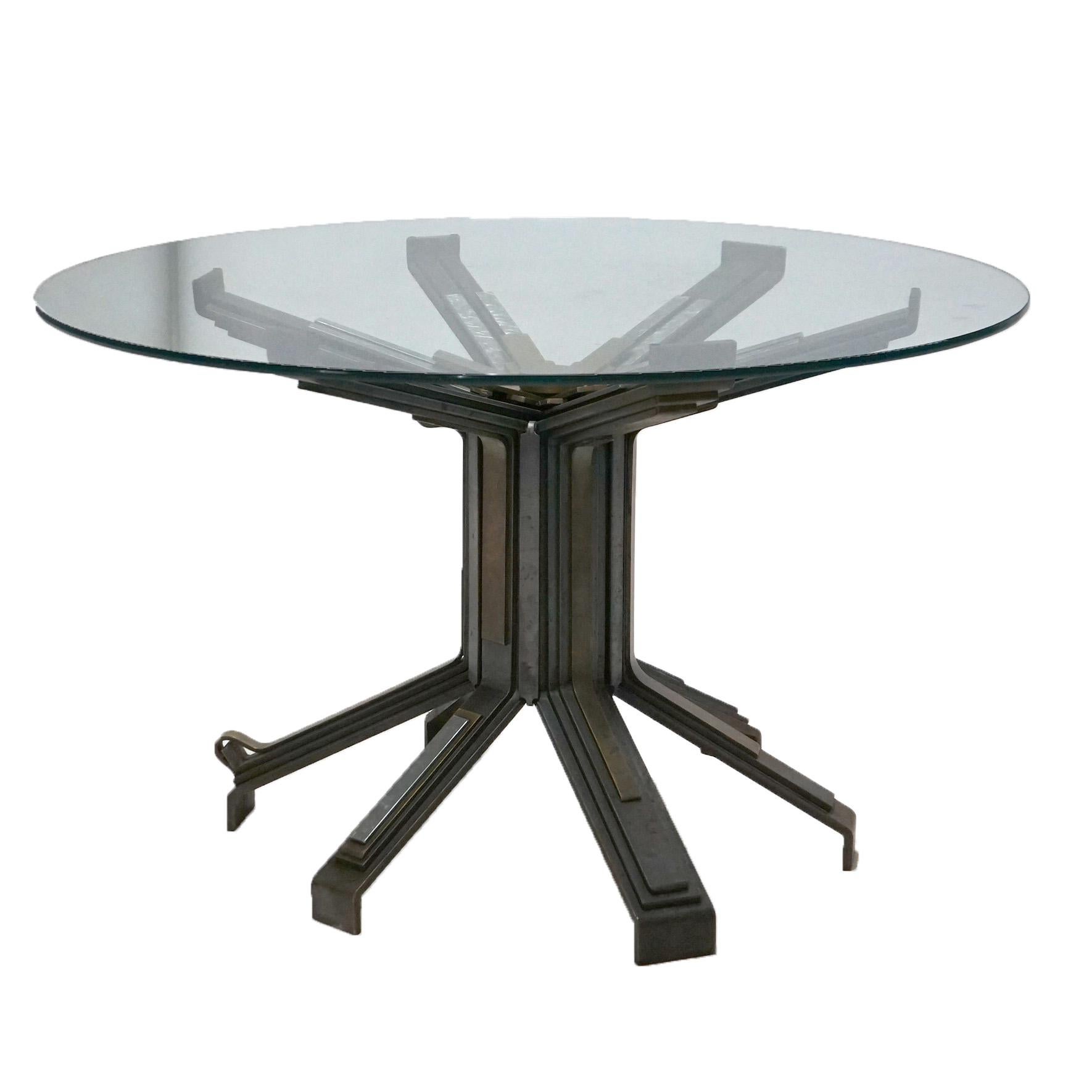 A Mid Century Modern Brutalist style table signed Monty W. Stephenson 1985
offers circular glass top over base with brushed steel, bronze & brass base in stylized sunburst form and raised on six spider legs, 1985.

Measures - 29.5