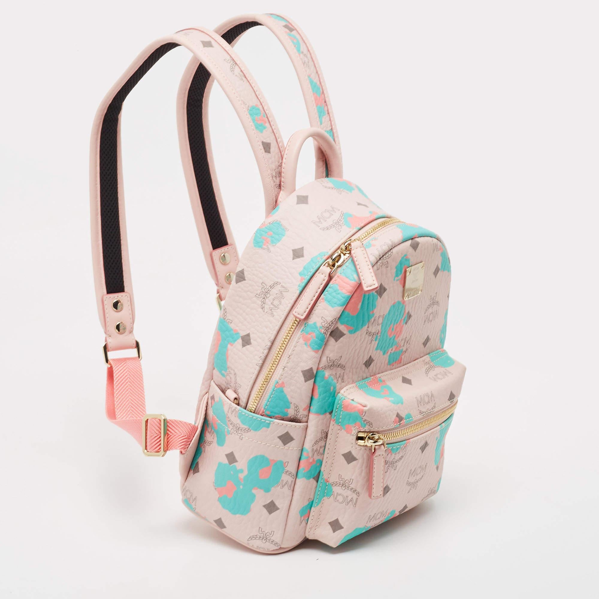 This MCM Stark backpack will come in handy for daily use or as a style statement. It is crafted from pink Visetos coated canvas and leather and designed with gold-tone studs on the sides. It features a front zip pocket and two slip pockets on the