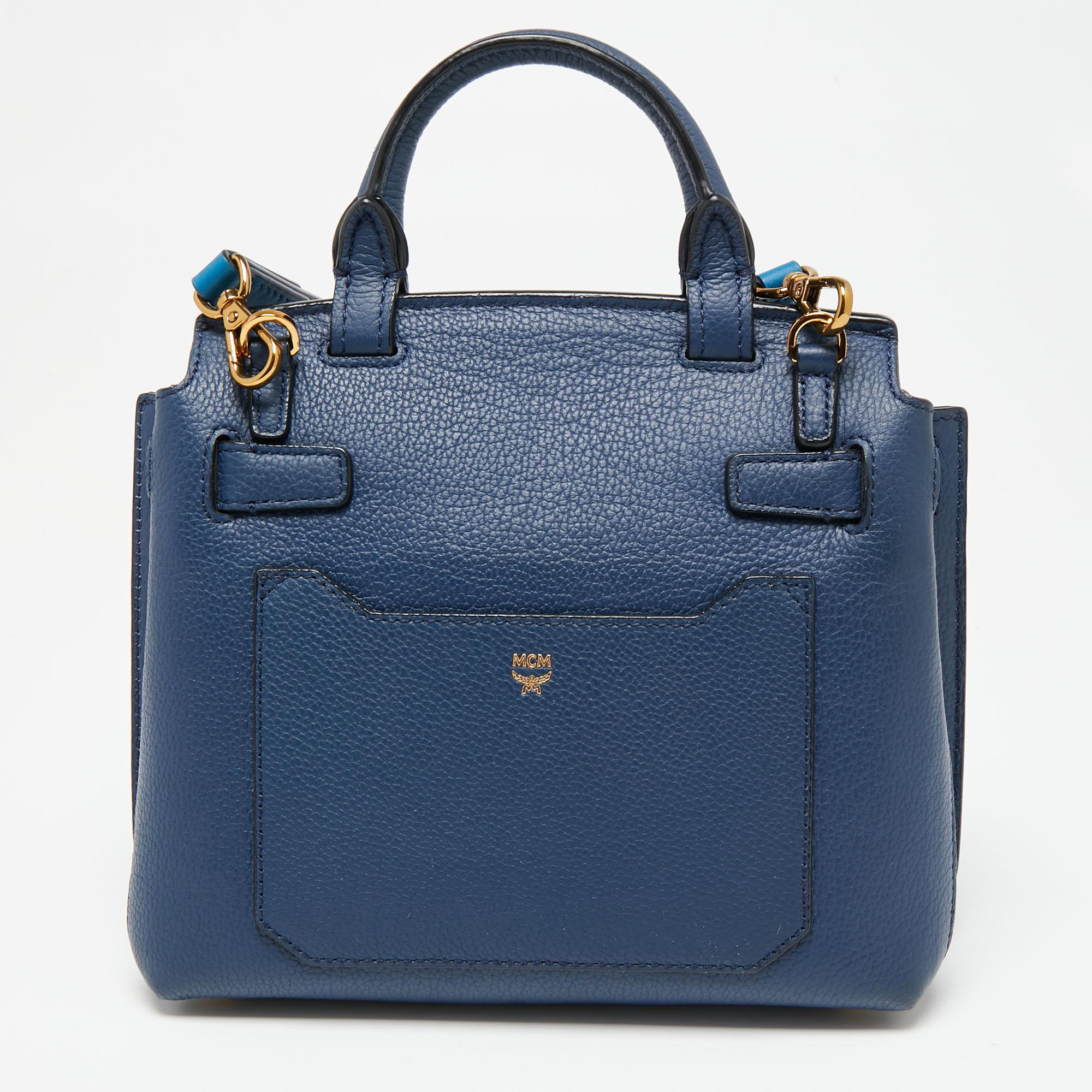 For your busy days, this MCM bag is totally perfect! It is crafted from navy blue leather and flaunts gold-tone details. The bag is finished with a top handle, a detachable strap, and a roomy Alcantara interior that can easily carry your