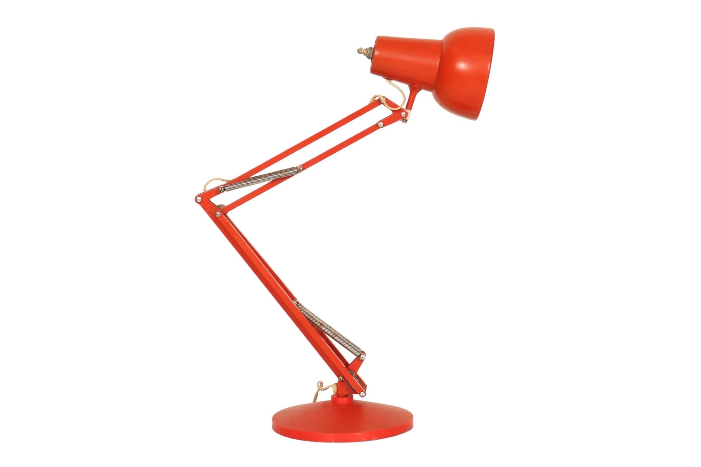 A Mid-Century Modern period architects desk lamp in a red gloss finish. Two spring mounted metal arms allow for the lamp to be angled in any direction. Marked “Norway” on the bottom arm. Rests in a heavy round metal base. Adjusts to between 11