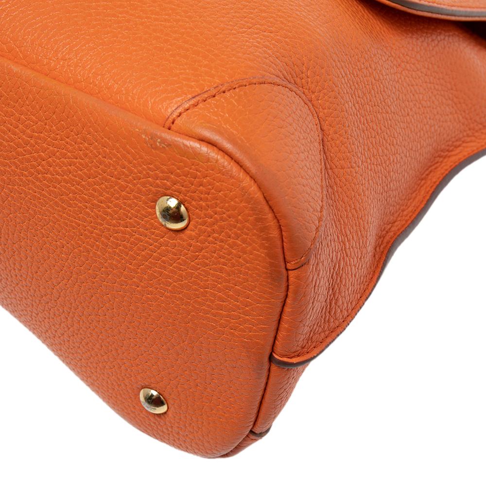 Crafted using leather, this orange MCM bag has a front flap that is detailed with brand elements and a twist-lock to secure the lined interior. It flaunts a single top handle and a shoulder strap. You can count on this MCM creation to be an ideal