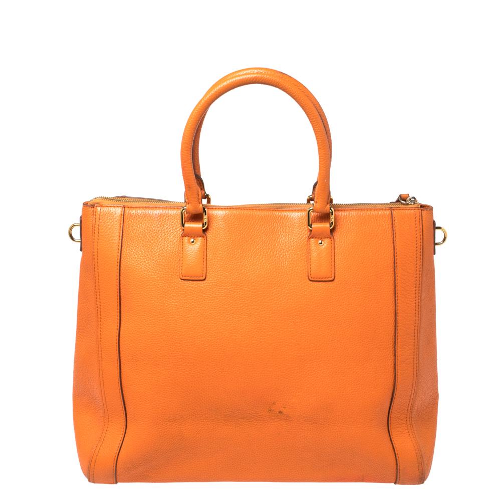 Designed with a chic appeal in a structured silhouette, this tote will add sophistication and elegance to your ensemble while carrying your essentials effortlessly. It is crafted with textured leather in an orange hue and features dual top handles