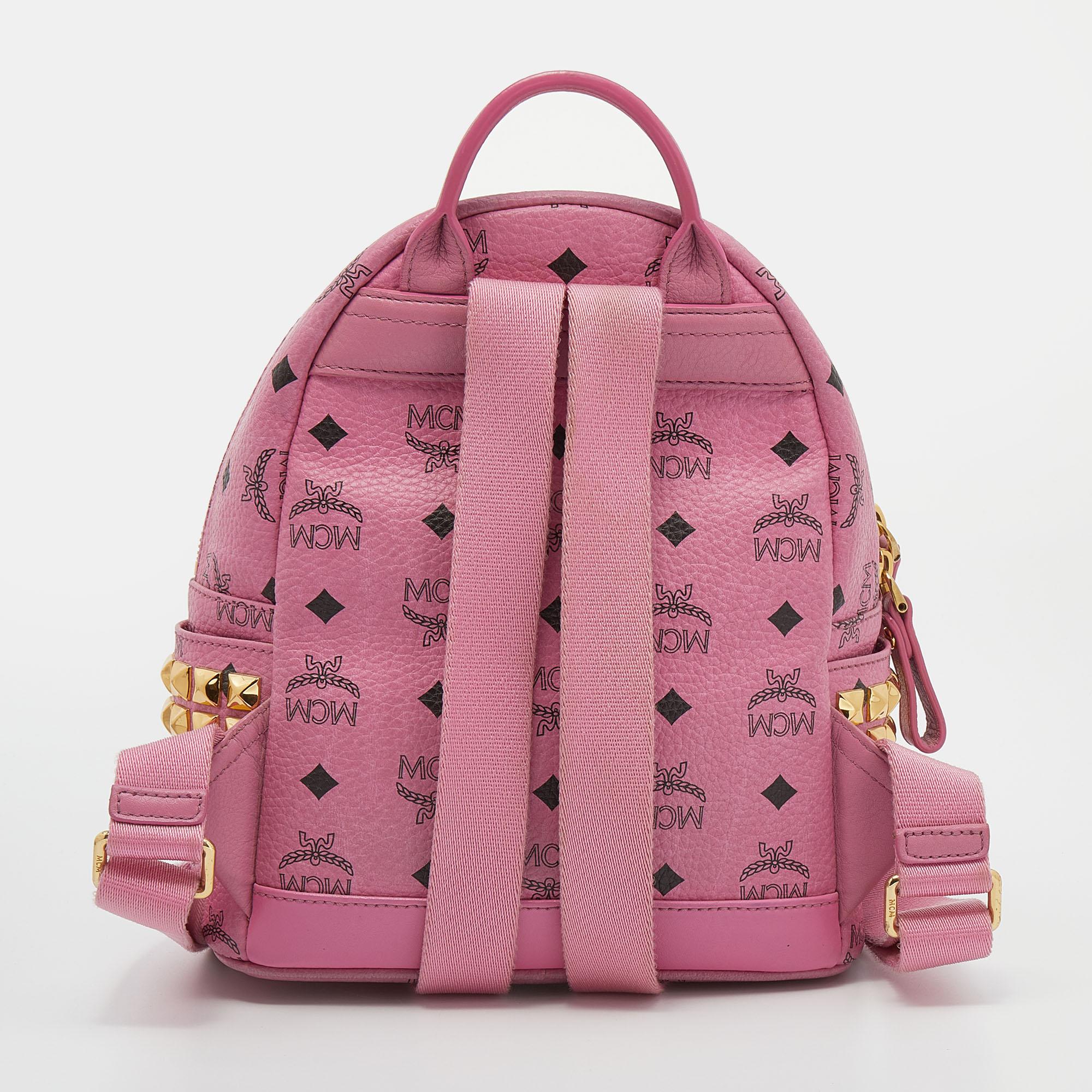 This stunning MCM backpack will come in handy for daily use or as a style statement. It is crafted from Visetos coated canvas and designed with studs, a front pocket, and a spacious interior secured by a zipper. Two shoulder straps and a small top