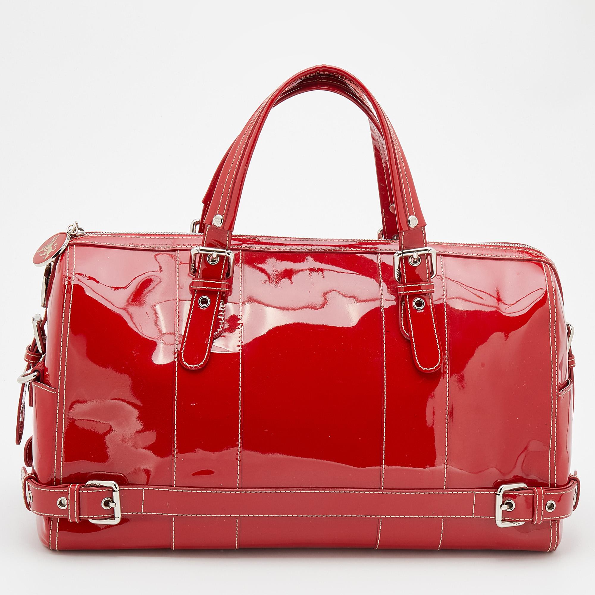 This MCM duffle bag is filled with functional details and is perfect for long days. Created from patent leather, it flaunts front exterior pockets with buckle detailing and its nylon-lined interior has more than enough space to house your daily