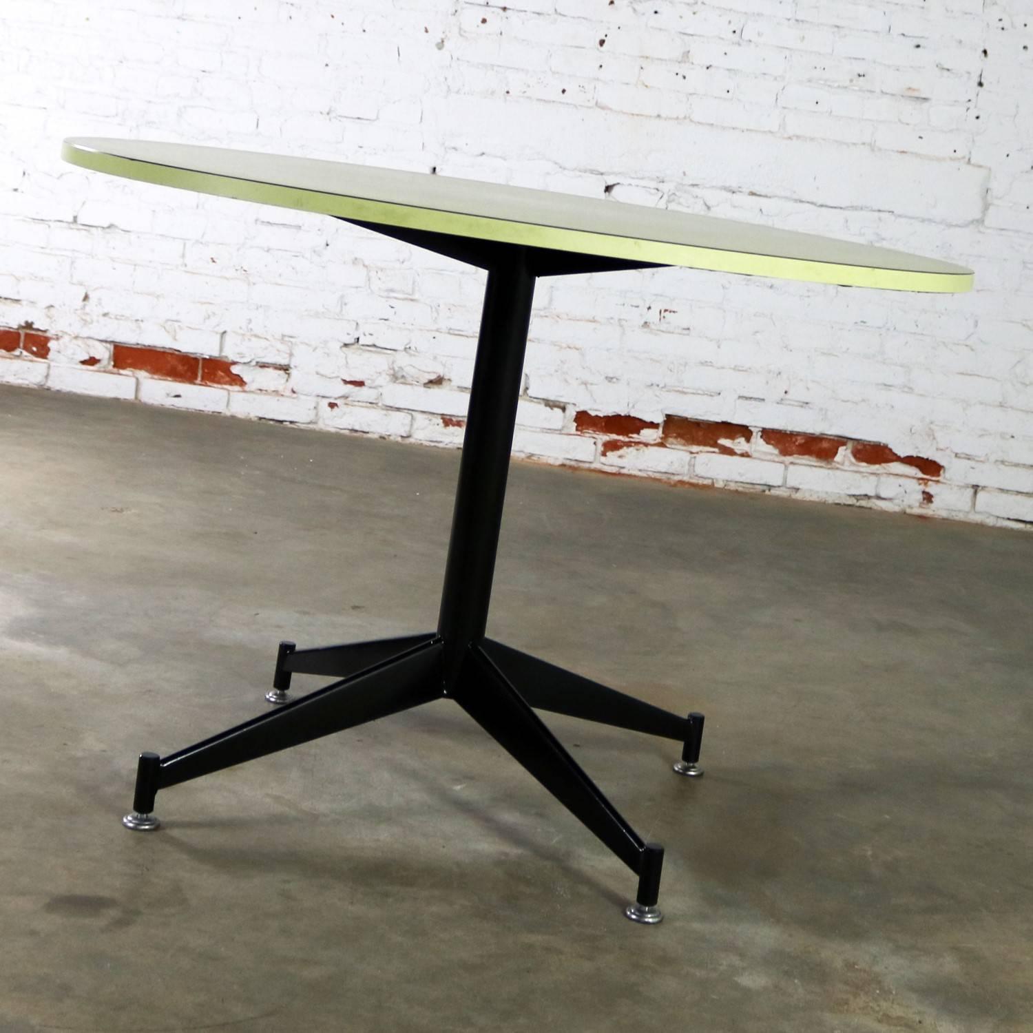 Handsome vintage MCM round dining table with avocado green laminate top and black painted steel central pedestal base. This table is unmarked, and the manufacturer is yet unknown, but it is done in the style of Paul McCobb for Directional. It is in