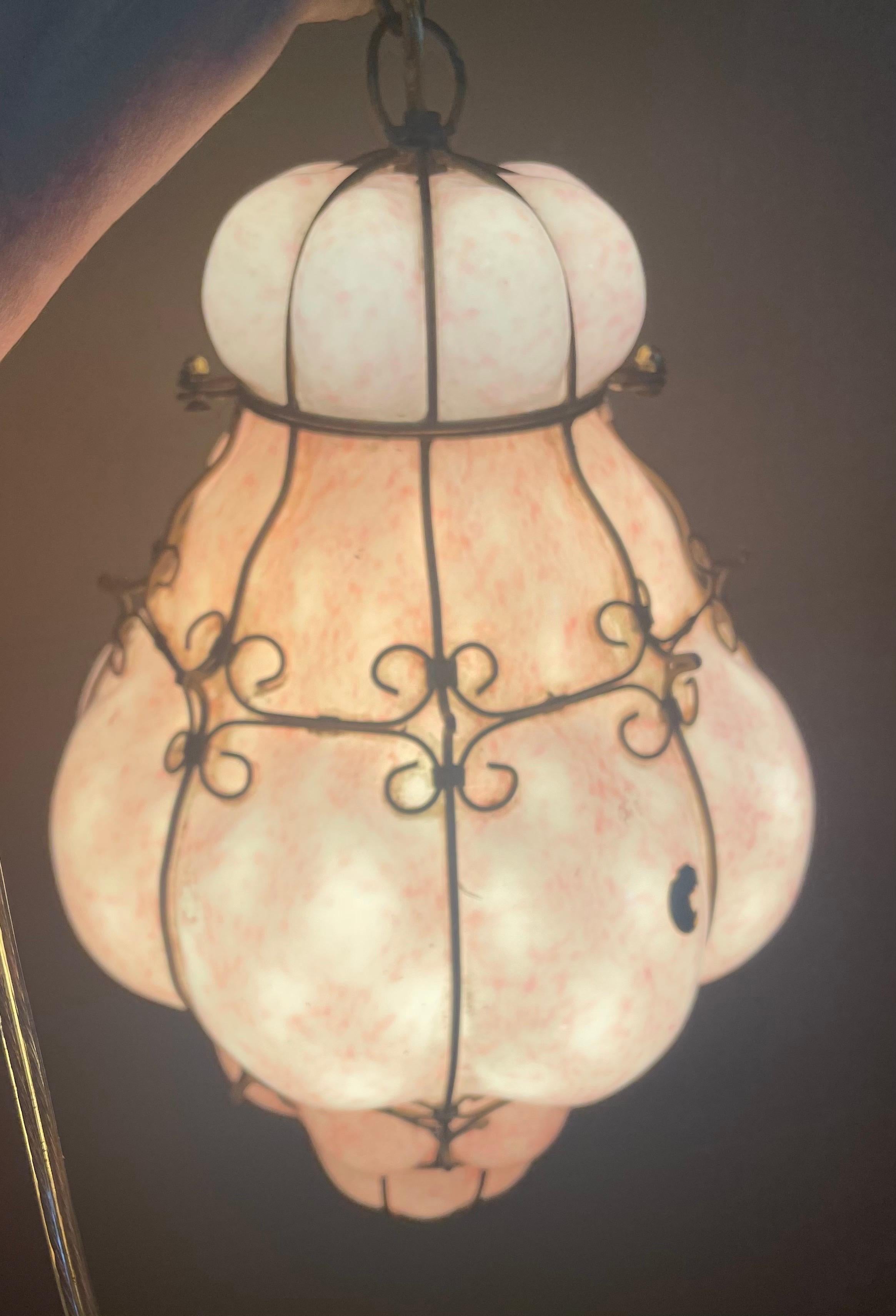 Si tratta di un vetro bianco assolutamente fantastico, incastonato in un vetro rosa screziato, soffiato a mano in una gabbia di filo metallico che, quando viene illuminata, emette un bellissimo bagliore caldo. Sarebbe favoloso in una camera da