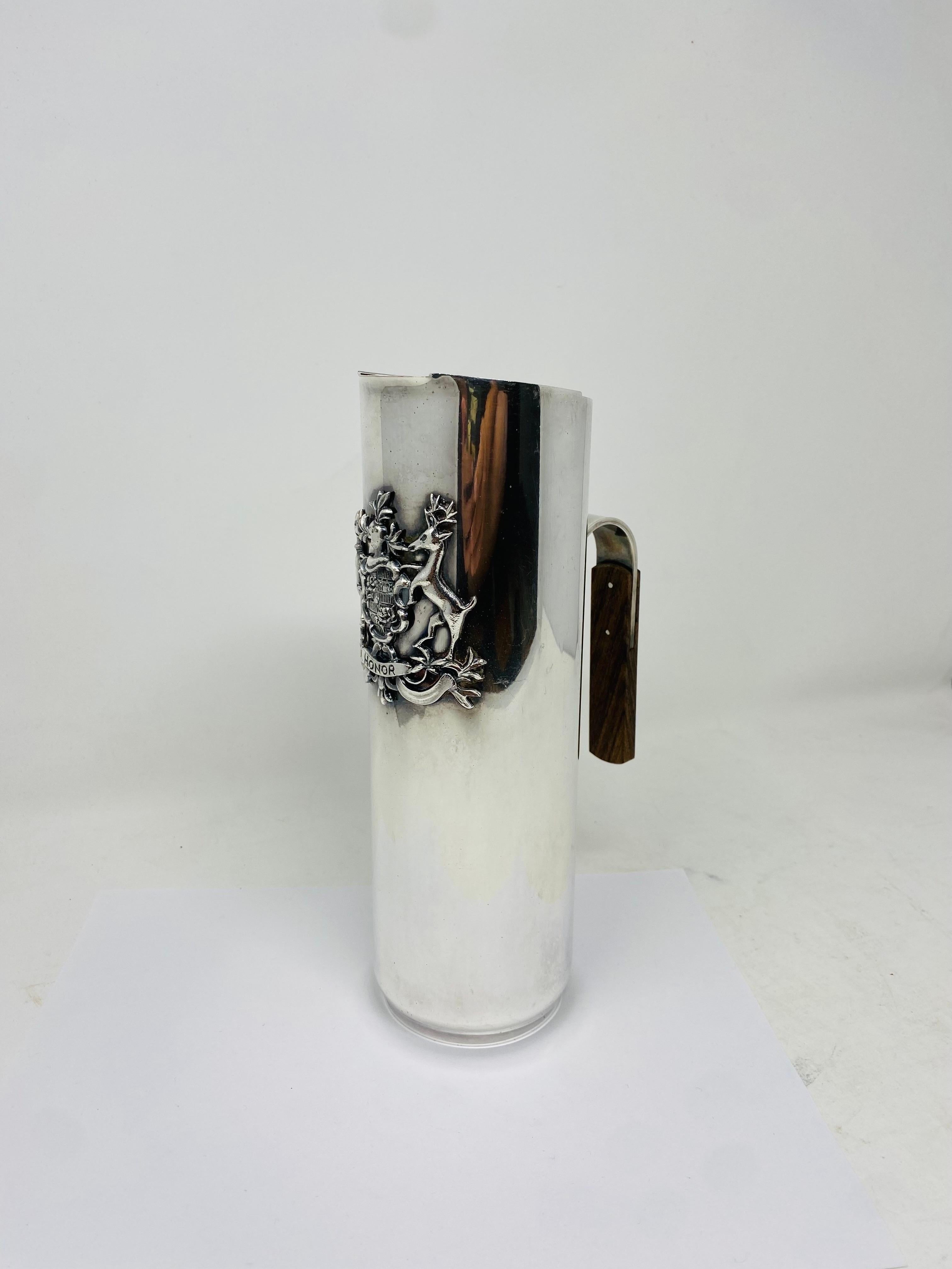 Esta preciosa jarra aporta un toque chic y sexy a tu colección de utensilios de bar. Fabricada en Italia, esta pieza tiene elementos de alto diseño artesanal. El cuerpo chapado en plata sostiene un impresionante escudo que alude a la atención y a la