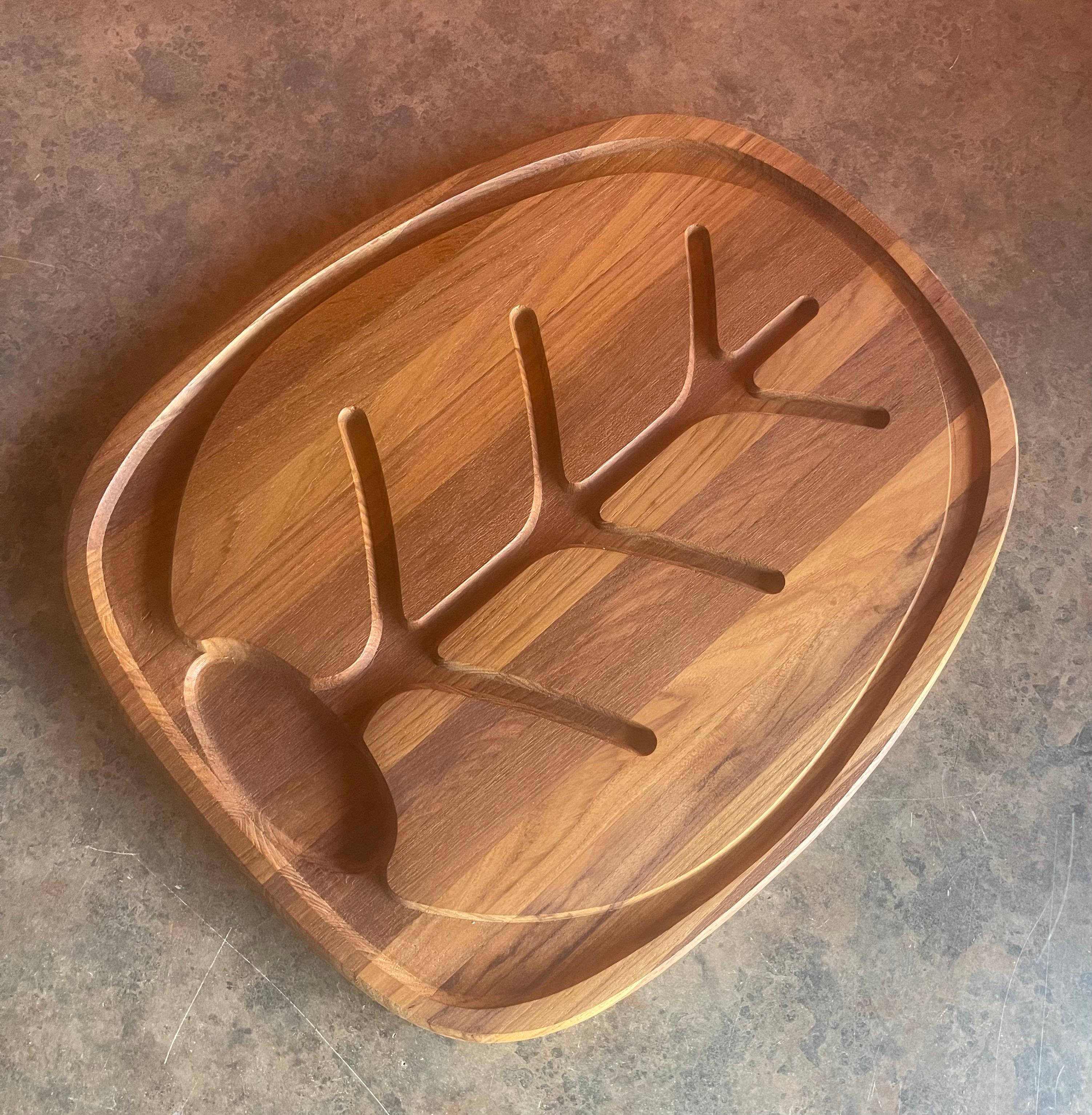 MCM staved teak carving / cutting board by Selandia, circa 1960s. The board brand new / old stock in original box and in excellent condition. The piece is very well made with a nice beveled edge and a built in drain for juices. The board is signed