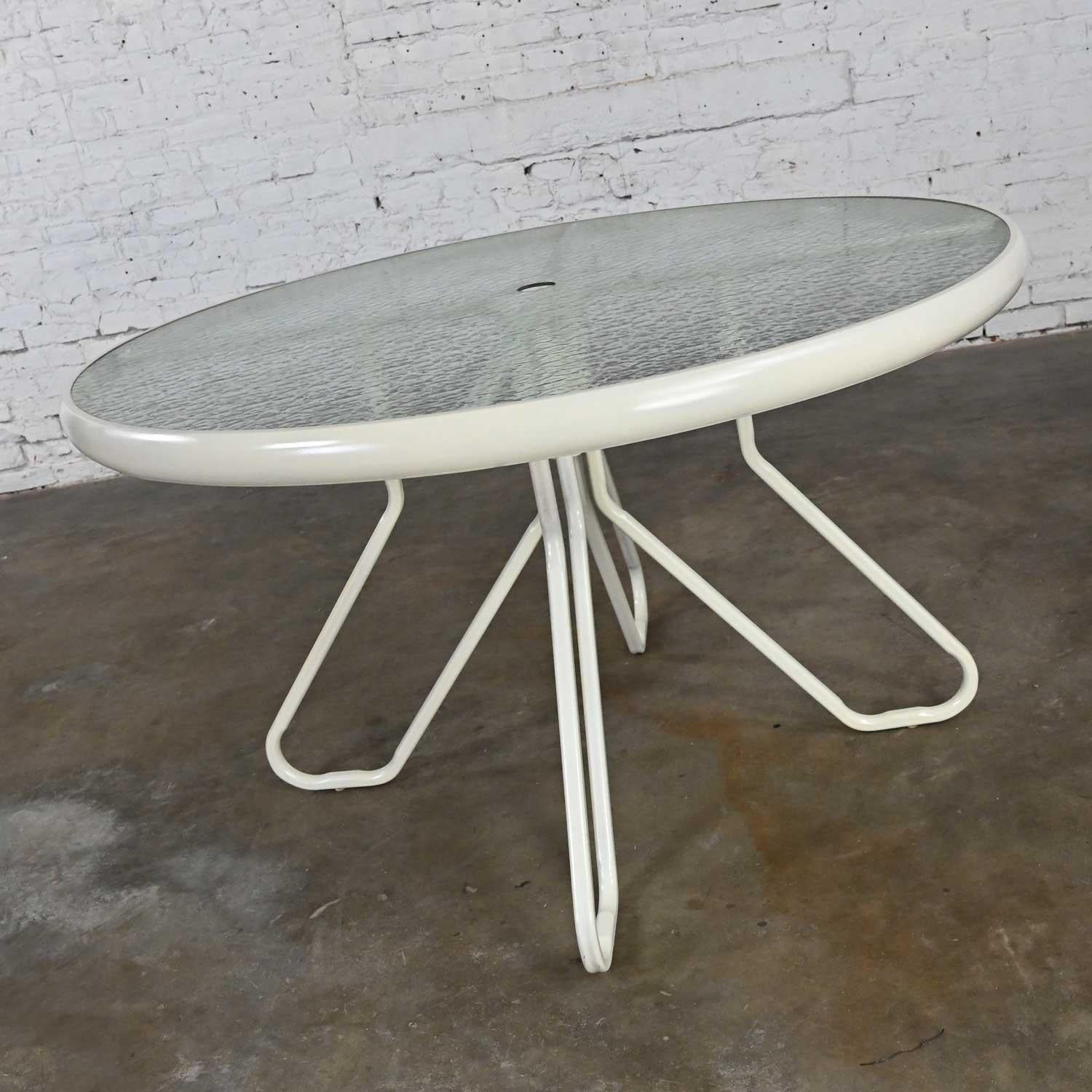 Fabulous vintage MCM outdoor table with paperclip style pedestal base and round dimpled glass top with a wide metal ring and an umbrella hole in the center. Beautiful condition, keeping in mind that this is vintage and not new so will have signs of