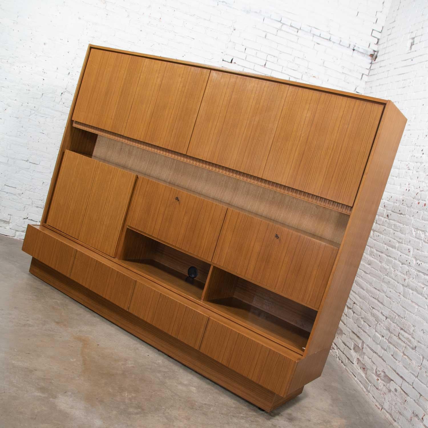 Handsome Mid-Century Modern German shrunk, wall unit, secretary, or liquor cabinet in beautiful teak veneer. This piece separates into two pieces upper and lower. It is in wonderful condition with no outstanding flaws. That is not to say it is