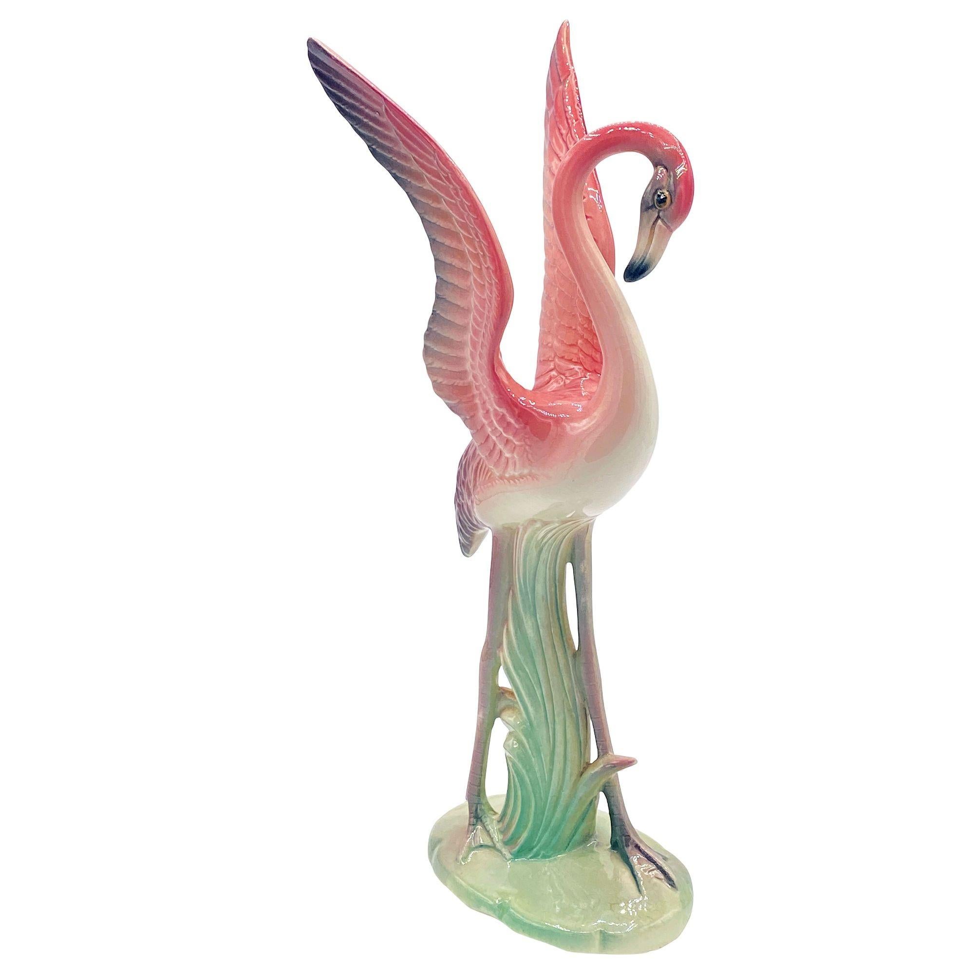 Mid-century pink and green matching California ceramic flamingo tabletop statues by Brad Keeler. The set features two beautifully detailed pink flamingos in lush green leaves and grass with a pink color. The large flamingo is landing on the ground,