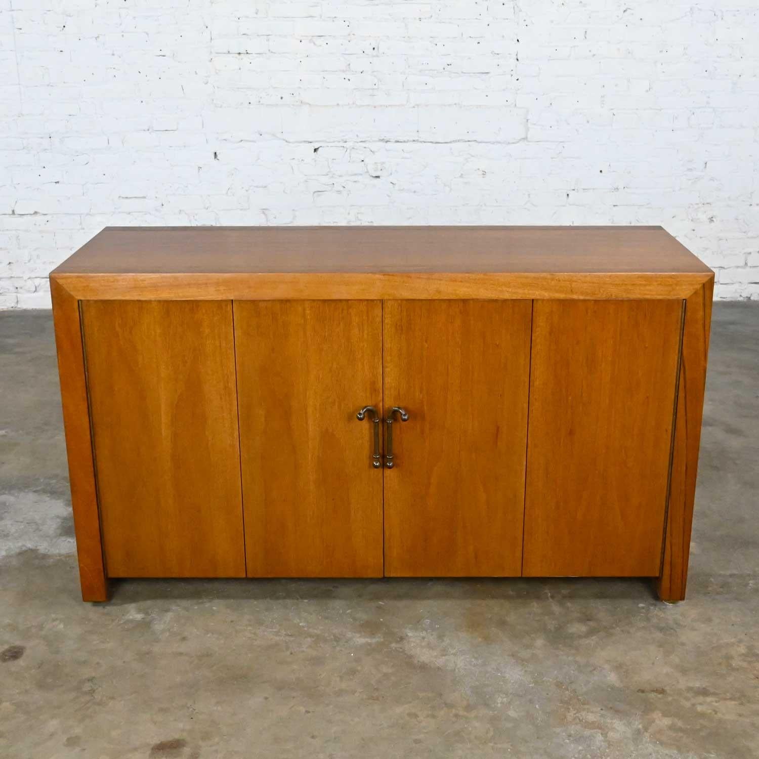 Fabulous Mid-Century Modern to Modern narrow walnut buffet console cabinet with bi-fold doors, 1 adjustable shelf, and antiqued brass handles. Beautiful condition, keeping in mind that this is vintage and not new so will have signs of use and wear.