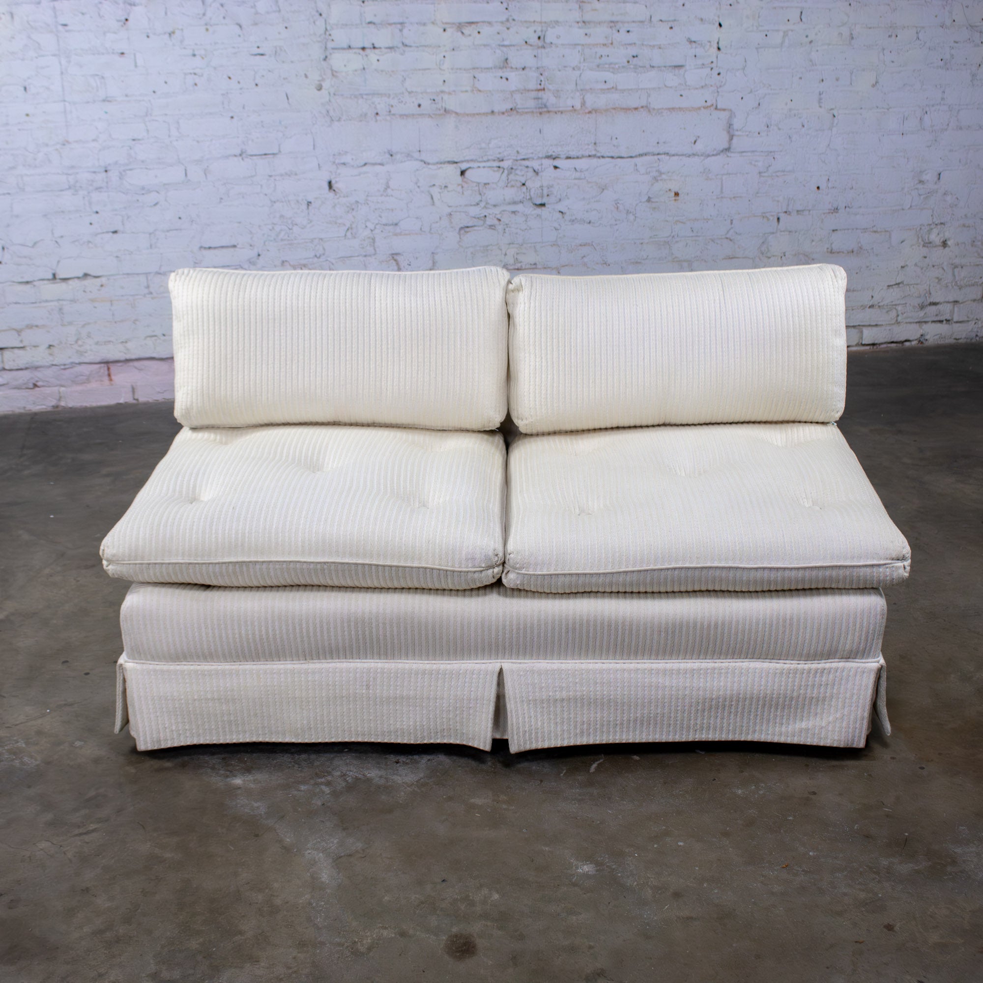 Precioso loveseat, banco o sofá sin brazos vintage de estilo MCM (Mid-Century Modern) a Moderno, con tapicería de rayas texturizadas en blanco roto, cojines de asiento y respaldo de espuma de poliéster con cremallera suelta, detalle de botones en
