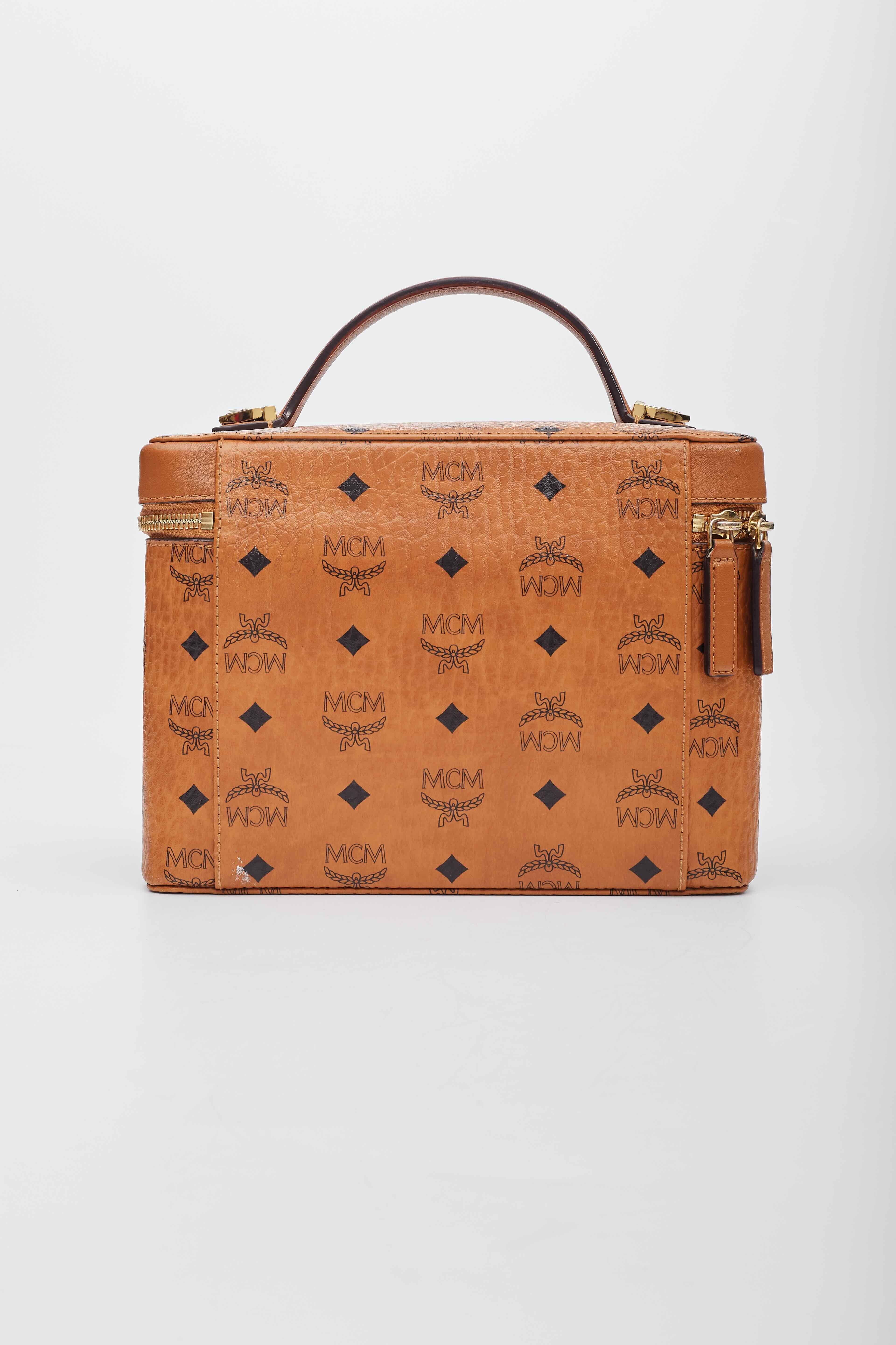 This bag is made from traditional MCM monogram visetos coated canvas. The case features a brown leather top handle and matching trim, an optional, adjustable shoulder strap and polished gold hardware. The wrap around zippers open to a beige