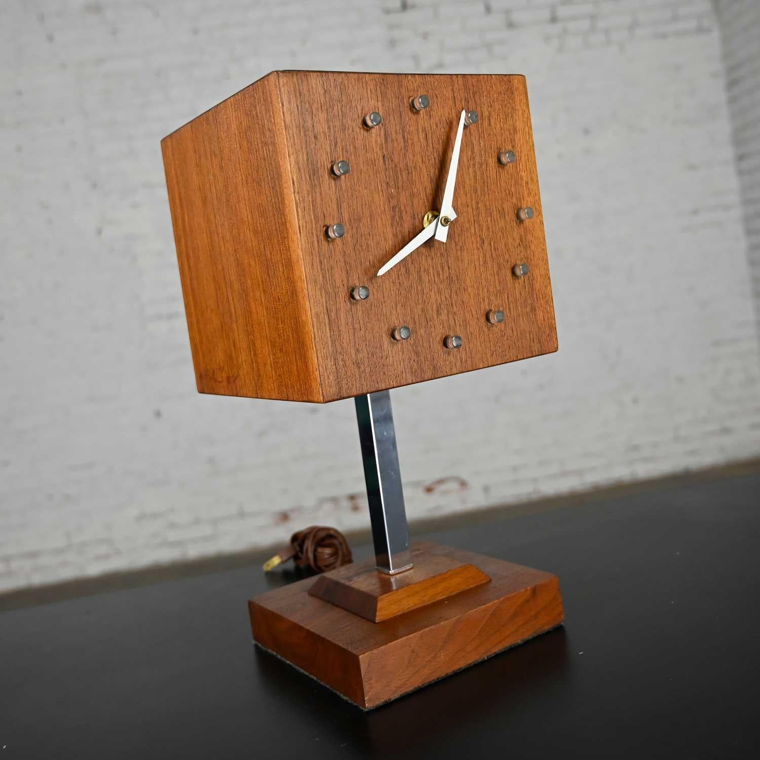 Awesome Mid-Century Modern walnut cube clock/lamp on a Stand comprised of a chrome shaft and square tiered walnut base by V. H. Woolums in the style of Howard Miller Clocks. Beautiful condition keeping in mind that this is vintage so will show signs