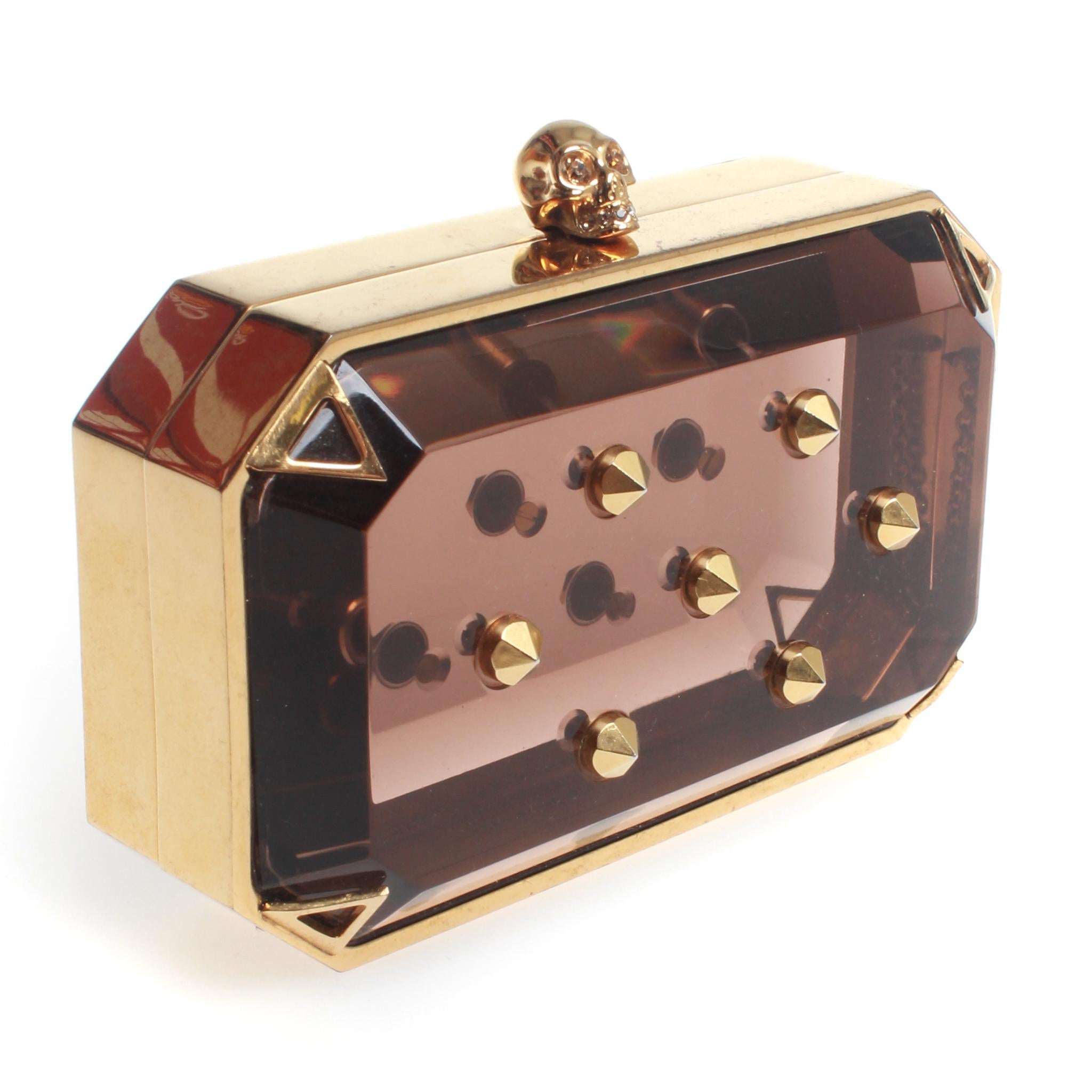 Collectible S/S14 Alexander McQueen amber plexiglass mini skull clutch embellished with gold toned studs. This box clutch features iconic skull head closure. Made in Italy.