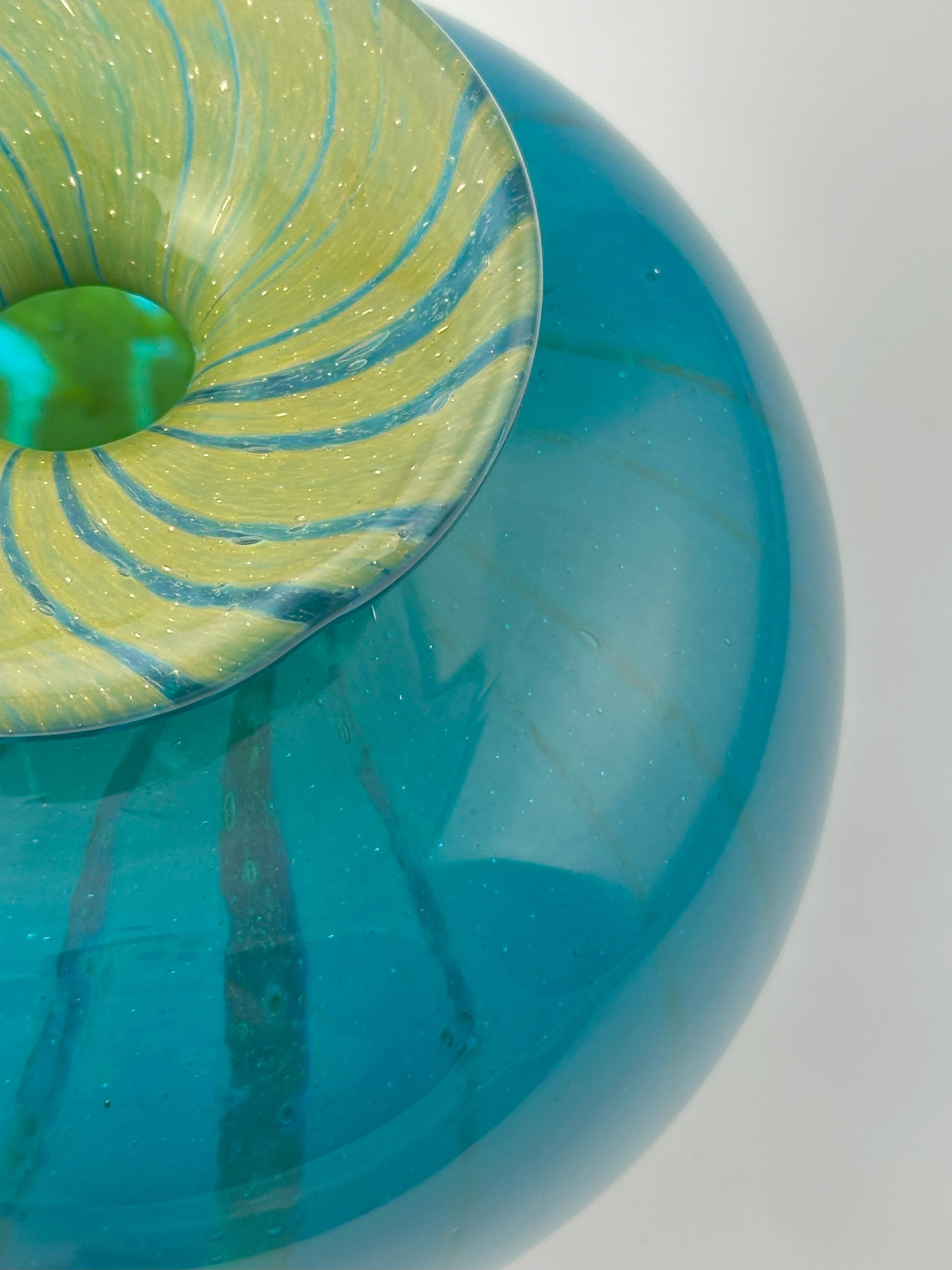A rare signed Mdina Glass vase from Malta, dated 1979, exemplifying the studio’s bold aesthetic during its formative years. 

This decorative squat bottle vase is worked in the celebrated ‘Ming’ pattern, with swirling bands of turquoise blue and
