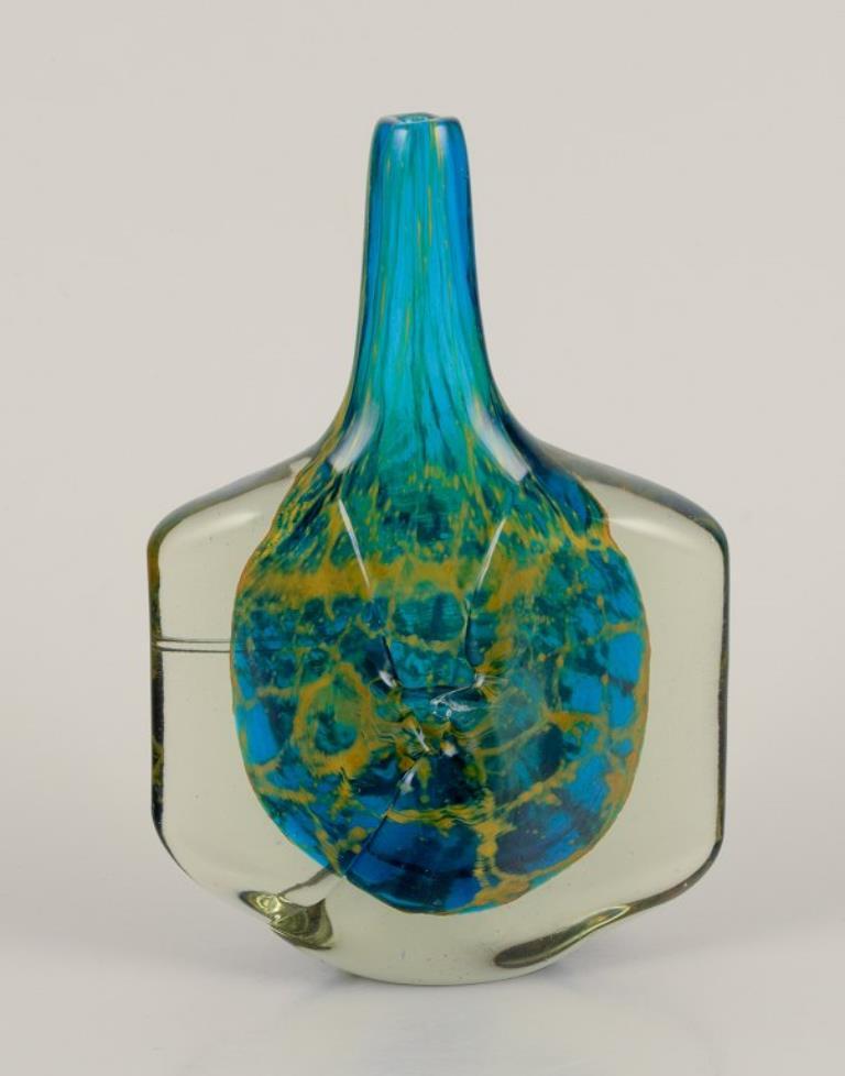 Mdina, Malta
Vaso in vetro artistico unico nel suo genere. 
Forma rotonda con collo stretto.
Vetro color fumo con motivo intarsiato in tonalità blu e gialle.
Firmato.
Ca. 1970.
Condizioni perfette.
Dimensioni: H. 17,5 cm x L. 11,5 cm.