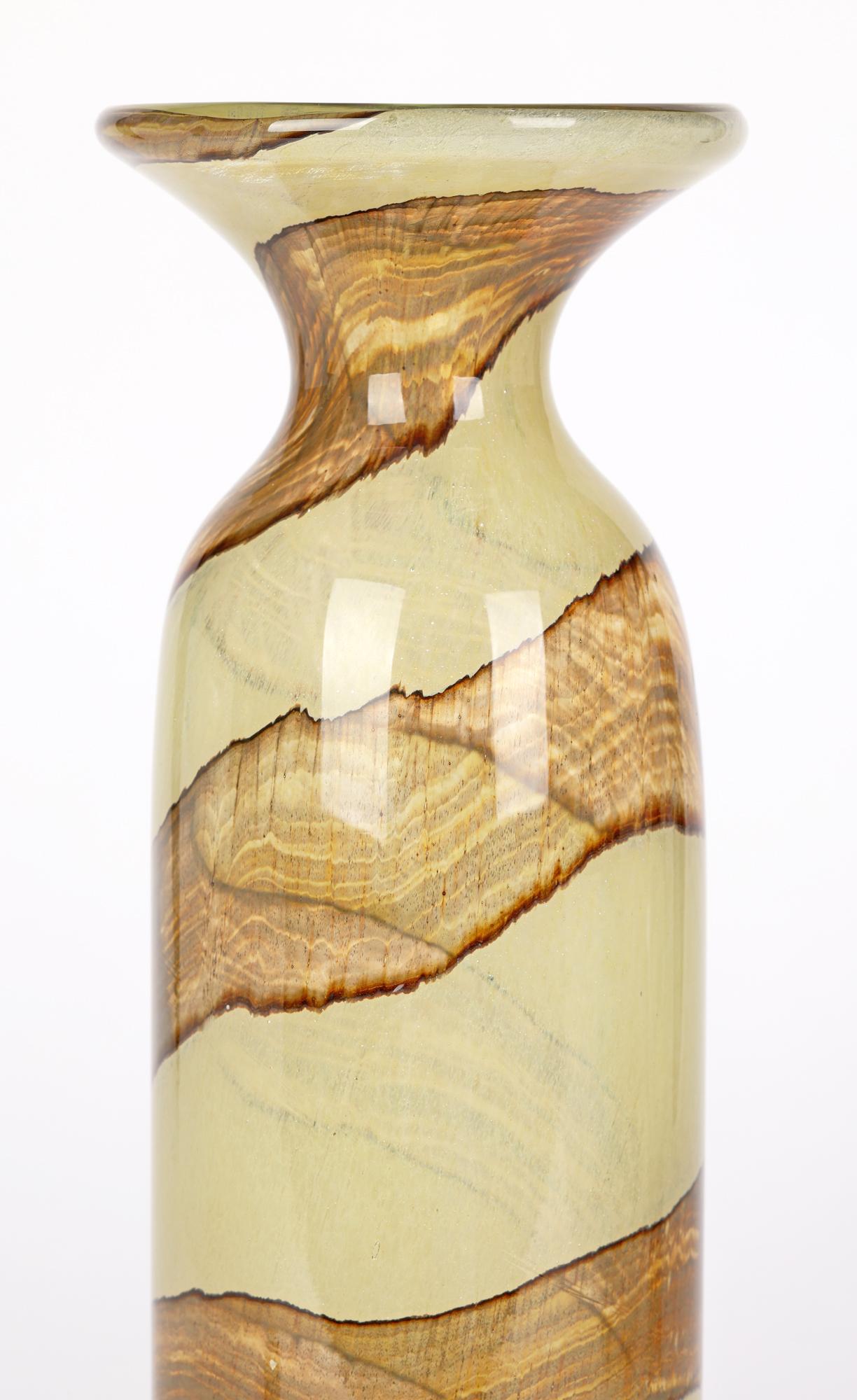 A tall and stylish Maltese art glass vase with a brown swirl design made at Mdina and designed by Michael Harris in the early 1970’s. The hand blown glass vase is of tall slender cylindrical shape with a narrow pinched neck and wide trumpet shaped