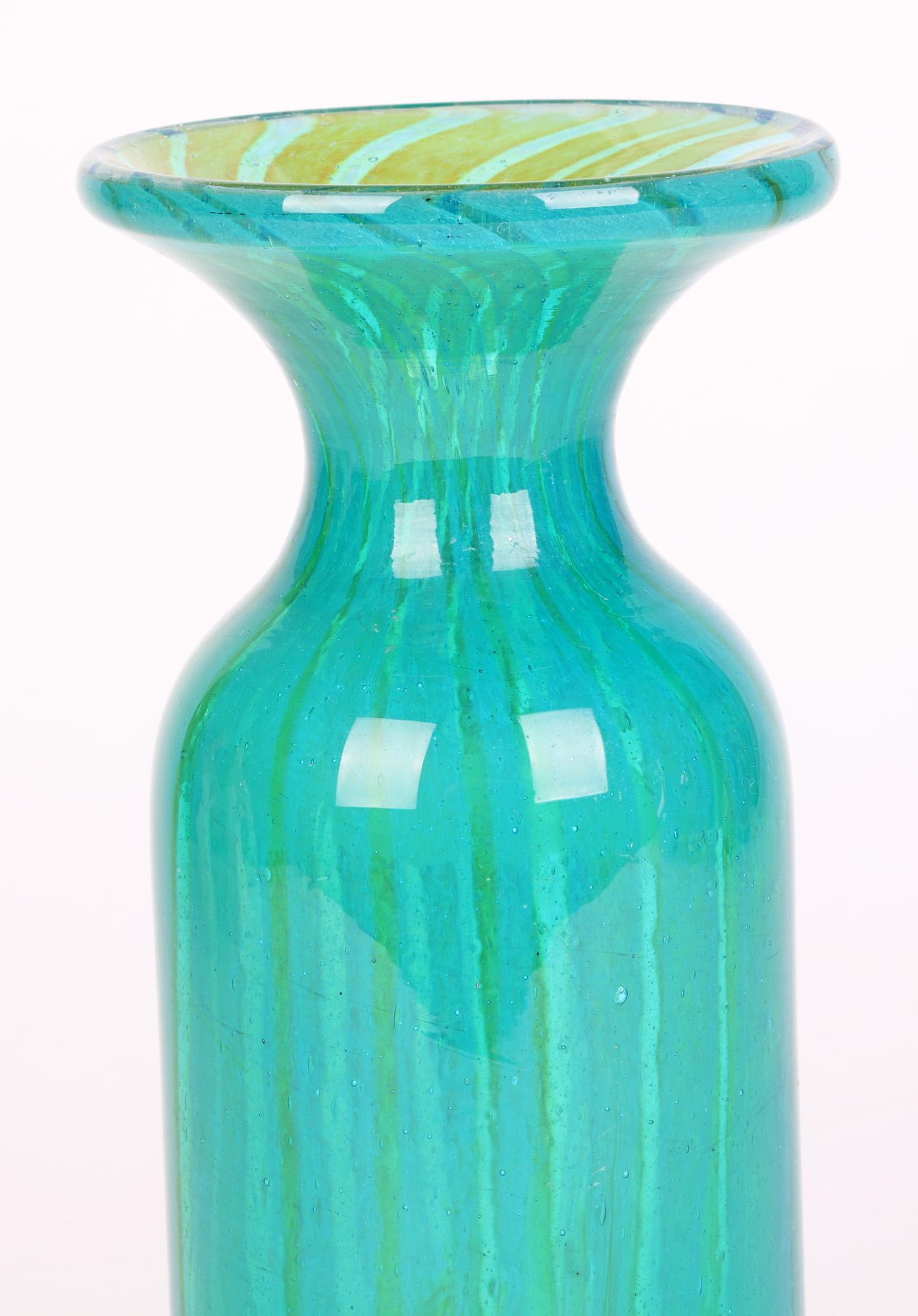 A tall and stylish Maltese art glass vase with sand colored streaks running through a blue body made by Medina and designed by Michael Harris in the early 1970’s. The hand blown glass vase is of tall cylindrical shape with a pinched neck and wide