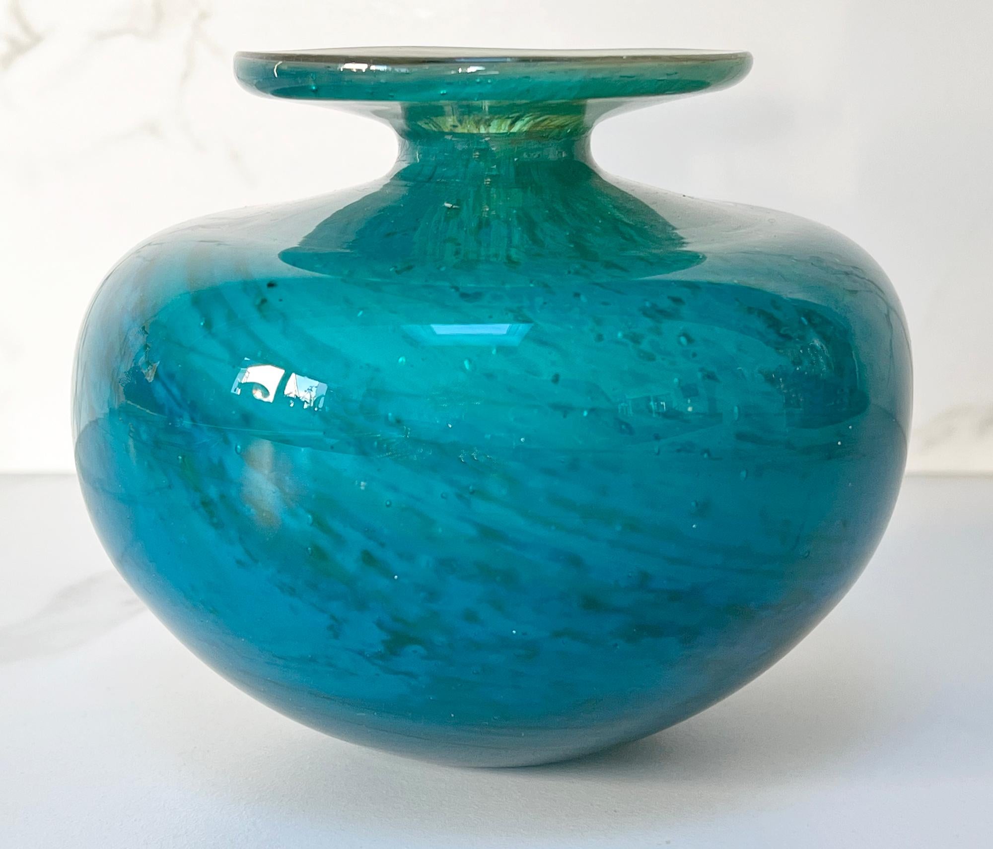 A stunning vintage Maltese Mdina art glass vase of squat rounded globular form with a narrow neck and wide rounded flattened top dating from the 1970's. The vase has rich blue turquoise with splashes of blue with sand colours to the top. The vase is
