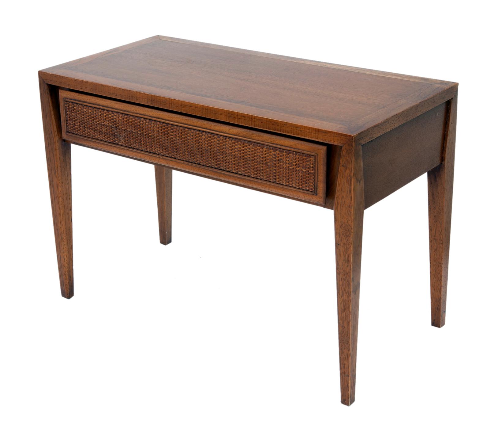 Mid Century Modern walnut side table by Century.
The table has four tapered legs & a single woven front drawer.