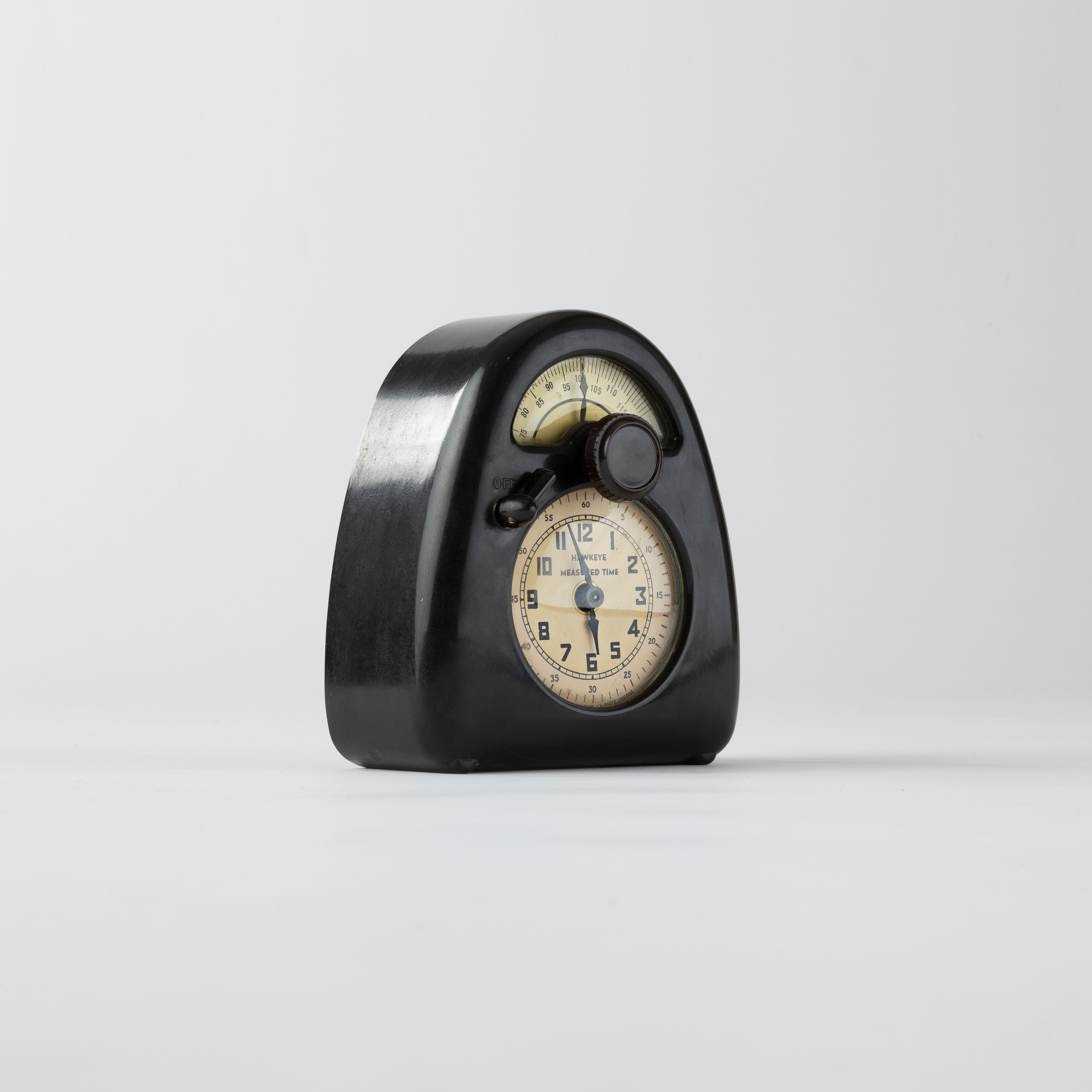 A « Measured Time » clock & kitchen timer by Isamu Noguchi, in bakelite, metal, enameled metal and printed paper, manufactured by Stevenson Manufacturing Company, La Porte, Indiana, United States. Reverse with the editor’s metal label. Model