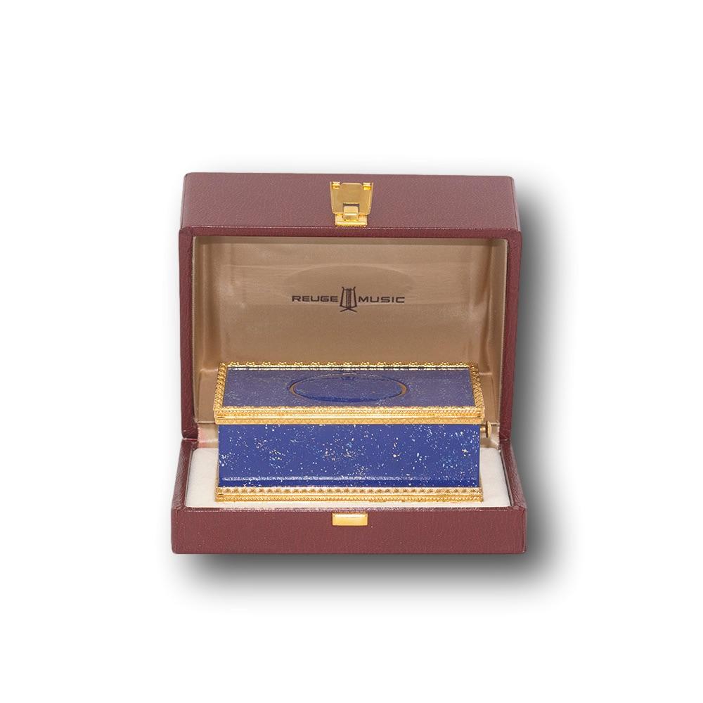Fine contemporary mechanical bird singing box by Reuge. The box beautifully crafted with an engine turned gilt metal frame stood upon four ball feet. To the panels simulated Lapis-Lazuli is delicately placed with layers of lacquer showing glints of