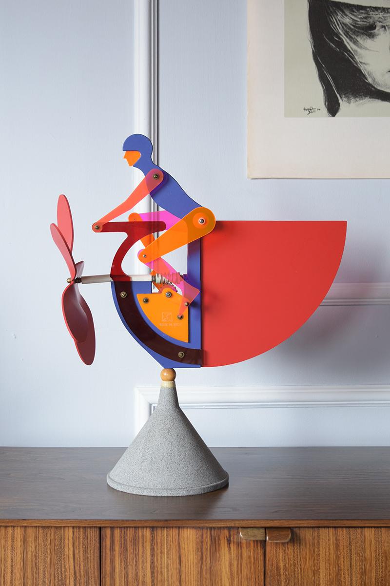 Discover our limited-edition kinetic sculpture from 1994, individually signed by the artist and one of only 100 globally. This exclusive piece depicts a man on a bicycle, equipped with a fully functional propeller that comes to life in the wind,