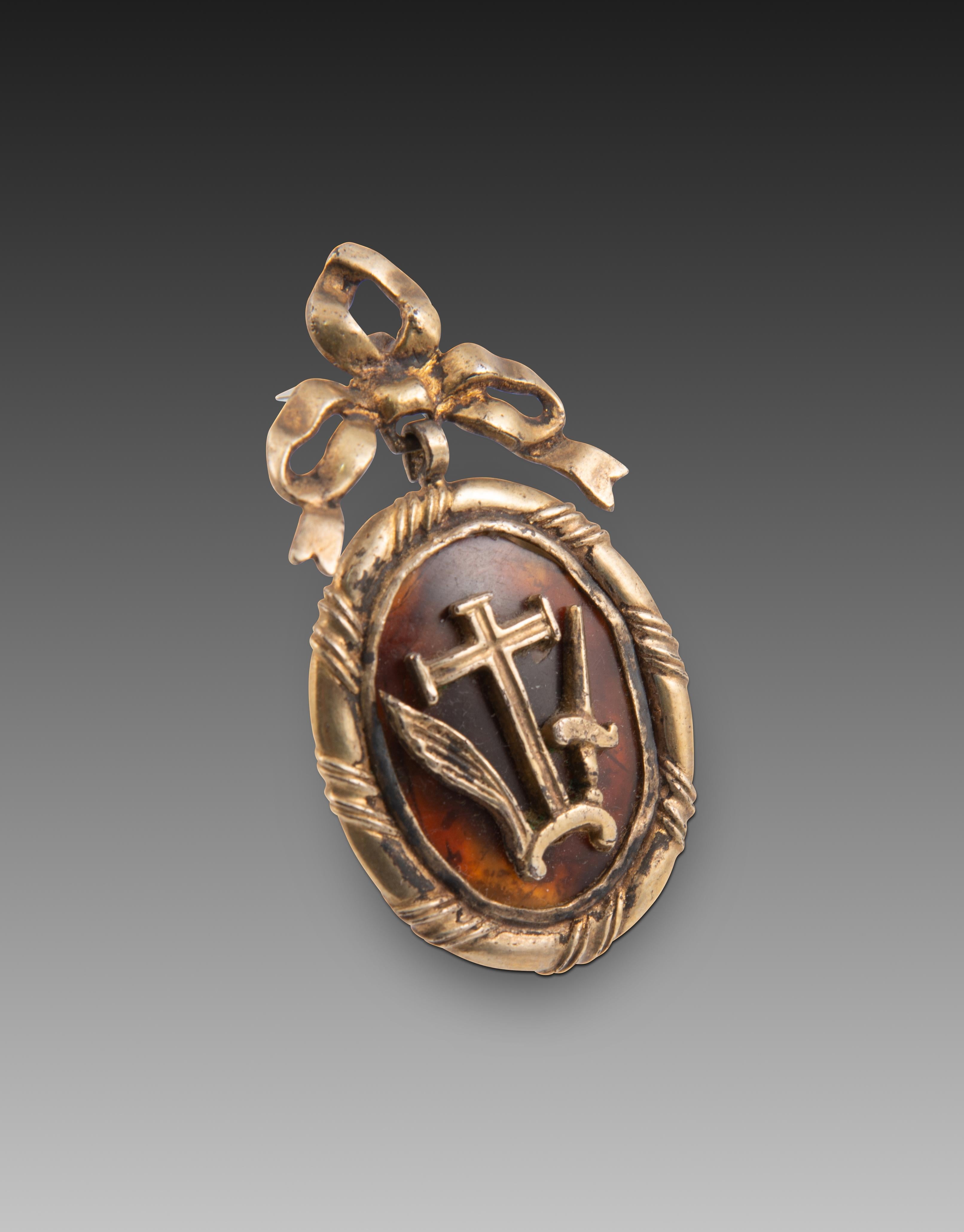 Medal. Mother-of-pearl, gilded silver. Spain, 18th century. 
Medal or habit with a bow at the top (behind which the medal's ring appears) and a plain frame with diagonal mouldings. On one side, on a tortoiseshell background, the emblems of the