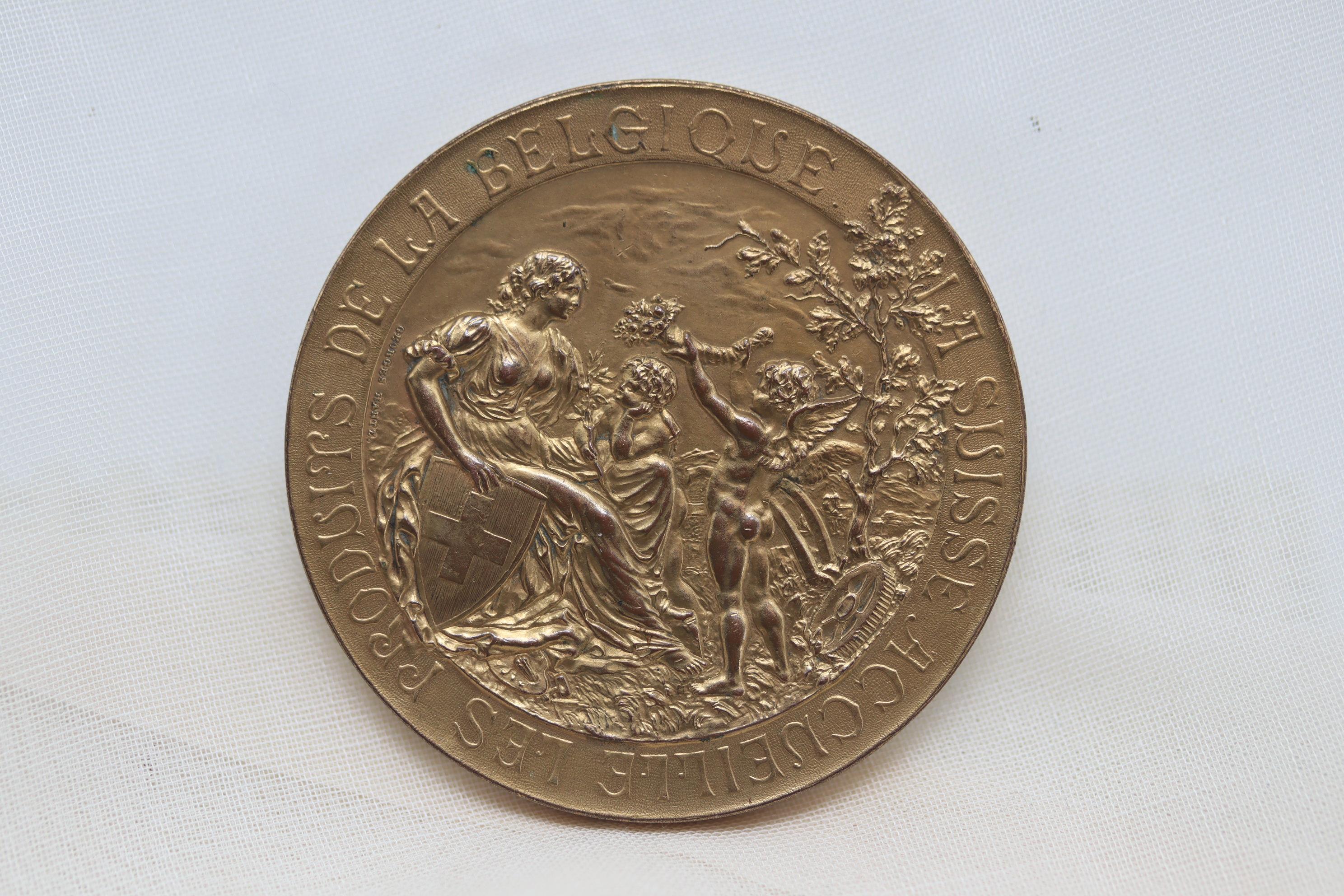 This very detailed medal was probably made for the Belgian delegation to the Geneva Exposition of 1896, perhaps as a sample. Whilst the lettering around the perimeter on the obverse is raised, the number 5 in the date 1895 is indented and The Beaux