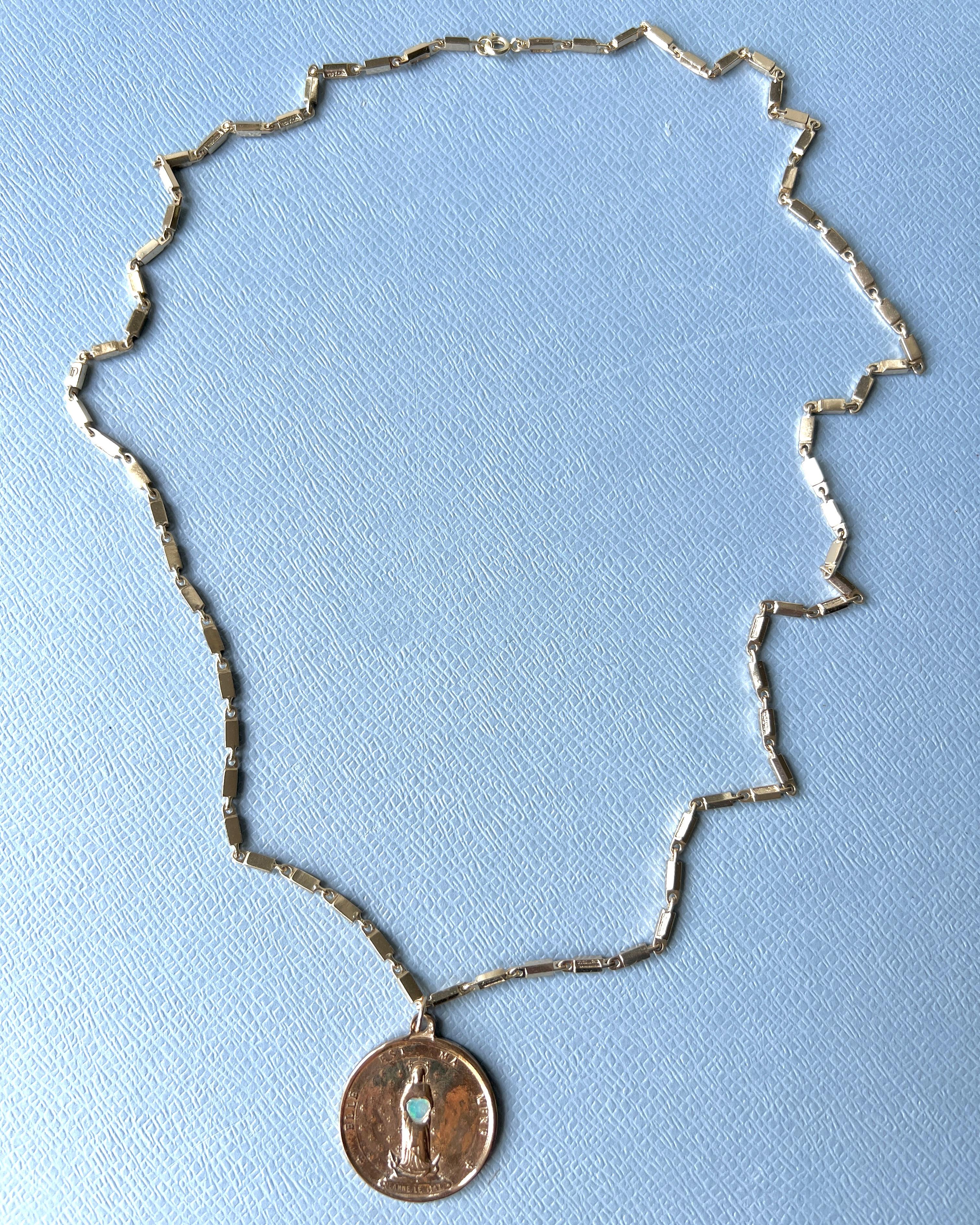 Medal Virgin Mary Chain Necklace Opal Heart

Jeanne le mat – She Is My Mother
Length: 28 inches
Designer: J DAUPHIN
Material: Medal in Bronze, Chain is 14 k Gold Plated Brass

A luminous heart opal is set at the center of this French bronze