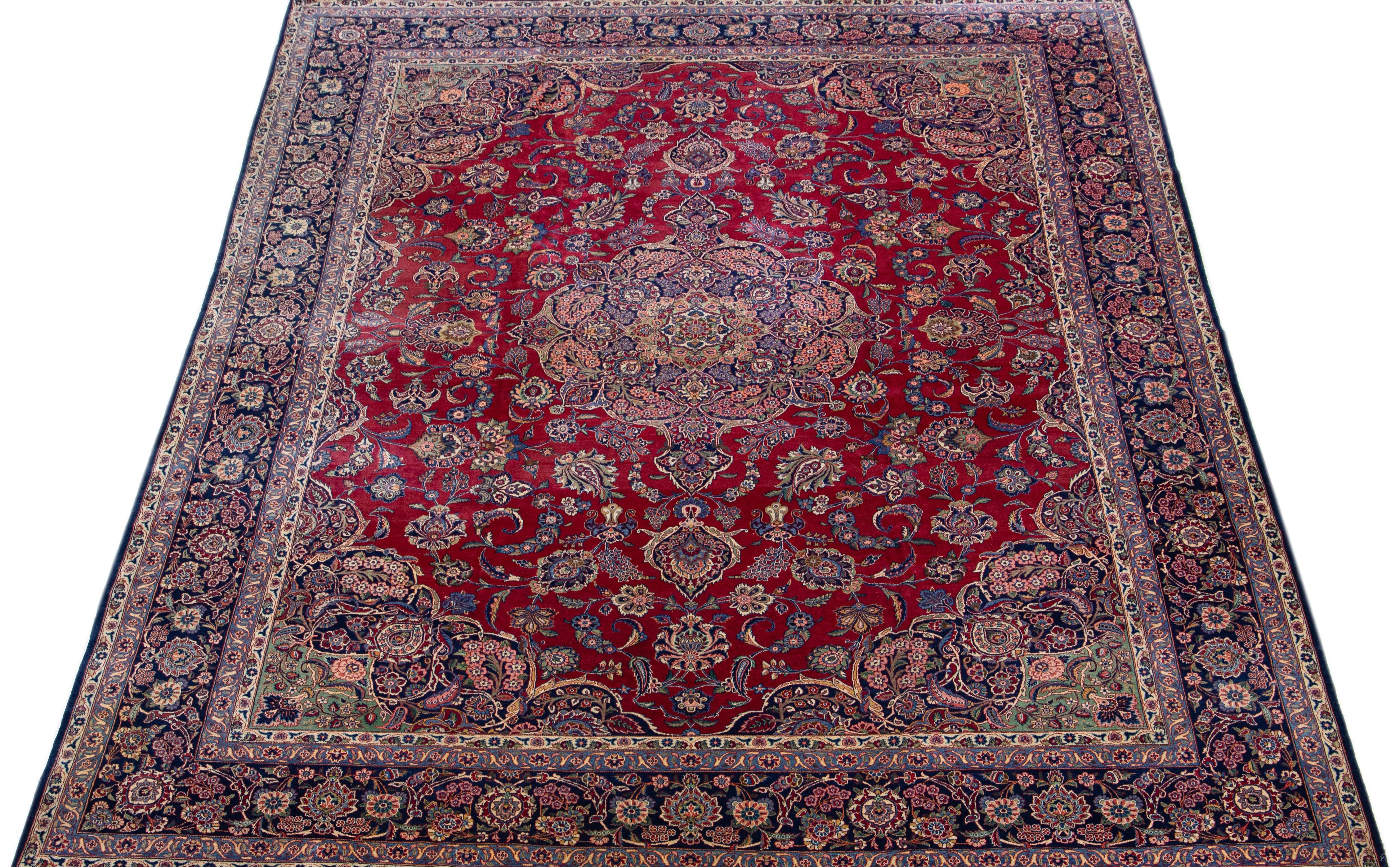 Beautiful Antique Kashan hand-knotted wool rug with a red color field. This Persian rug has a blue designed frame with accents in a gorgeous classic floral design. 

This rug measures: 10'6