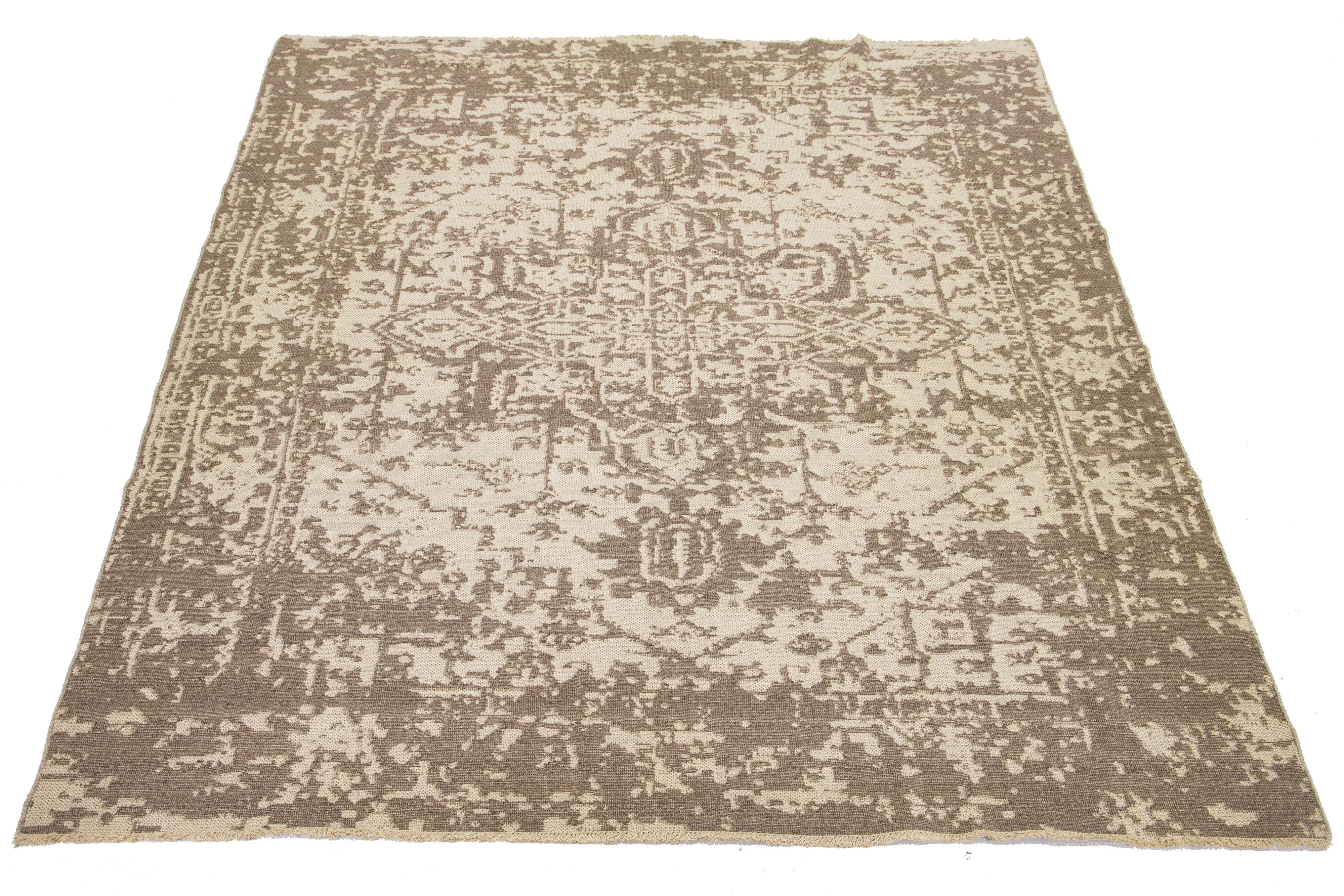 This hand-loomed wool rug features a beautiful beige background with a medallion motif in brown that covers the entire rug. 

This rug measures 9'6