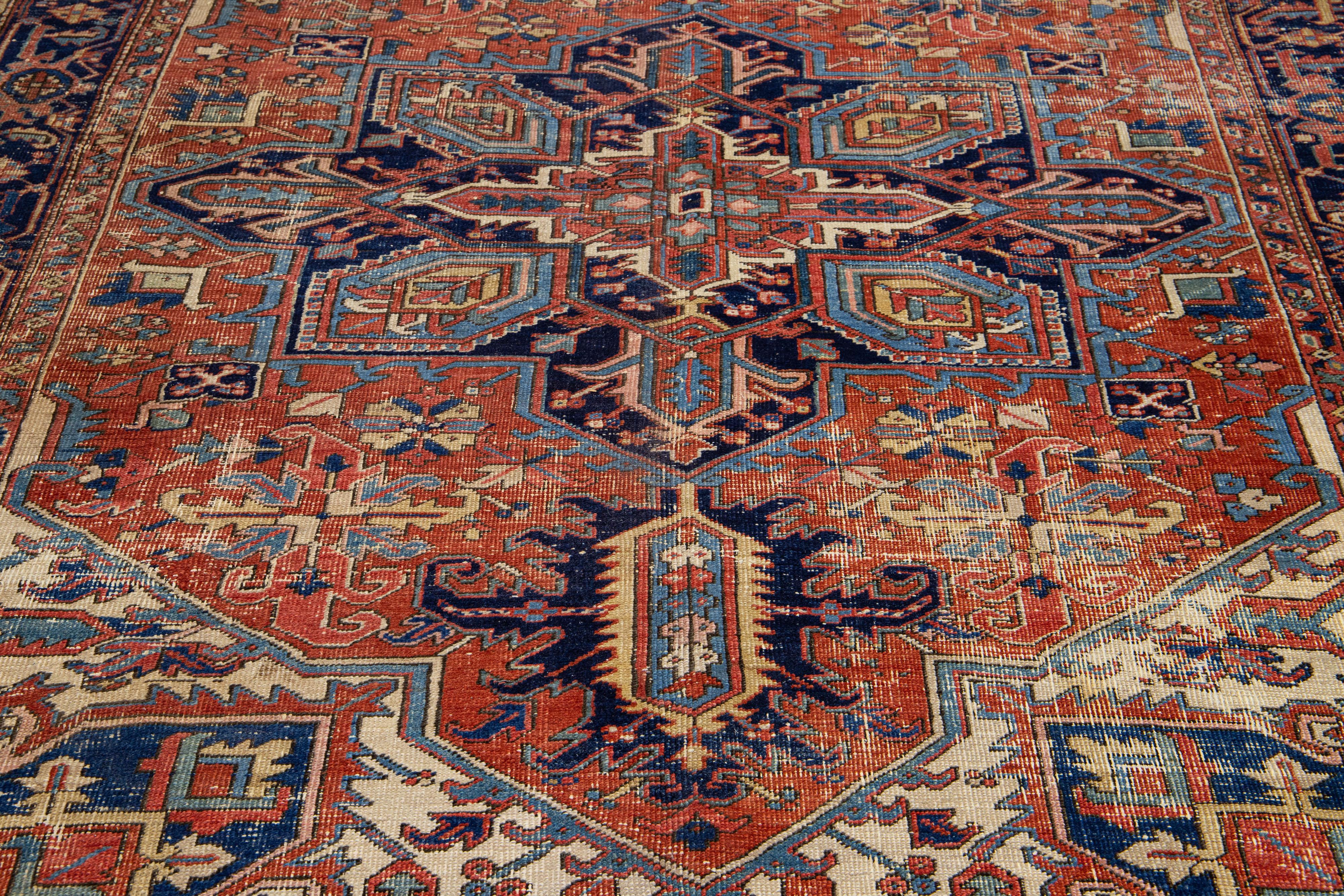 Beautiful vintage Heriz hand-knotted wool rug with a red-rust color field. This Persian rug has multi-color accents in a gorgeous all-over geometric floral medallion design.

This rug measures 7'3