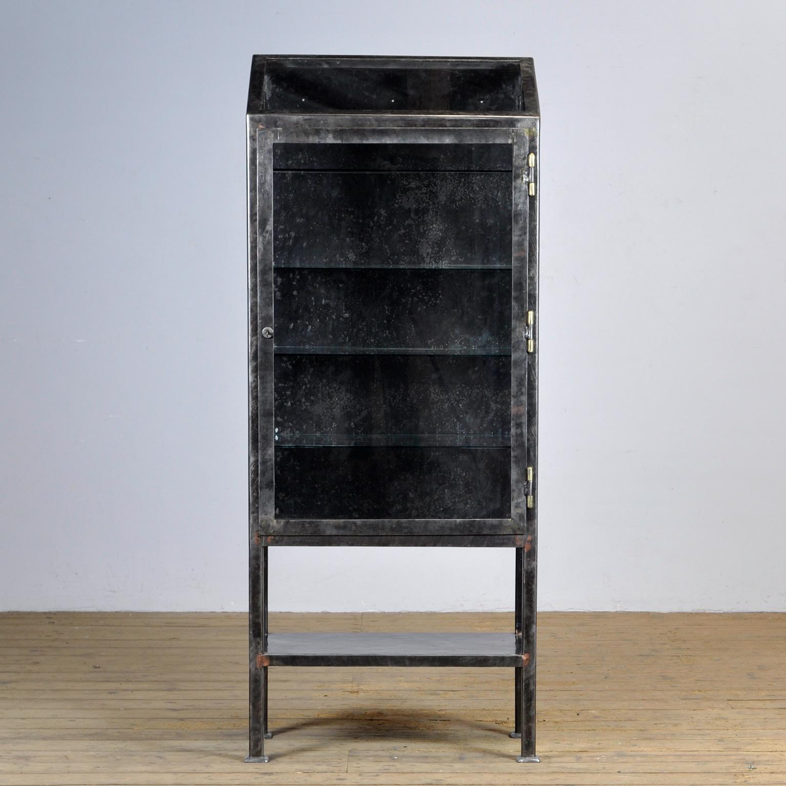 Heavy iron cabinet, made around 1920 with bronze details. The cabinet has been stripped to the metal and treated against rust. The cabinet has been used in a laboratory. The reason for the sloping top is that no hazardous substances could be placed