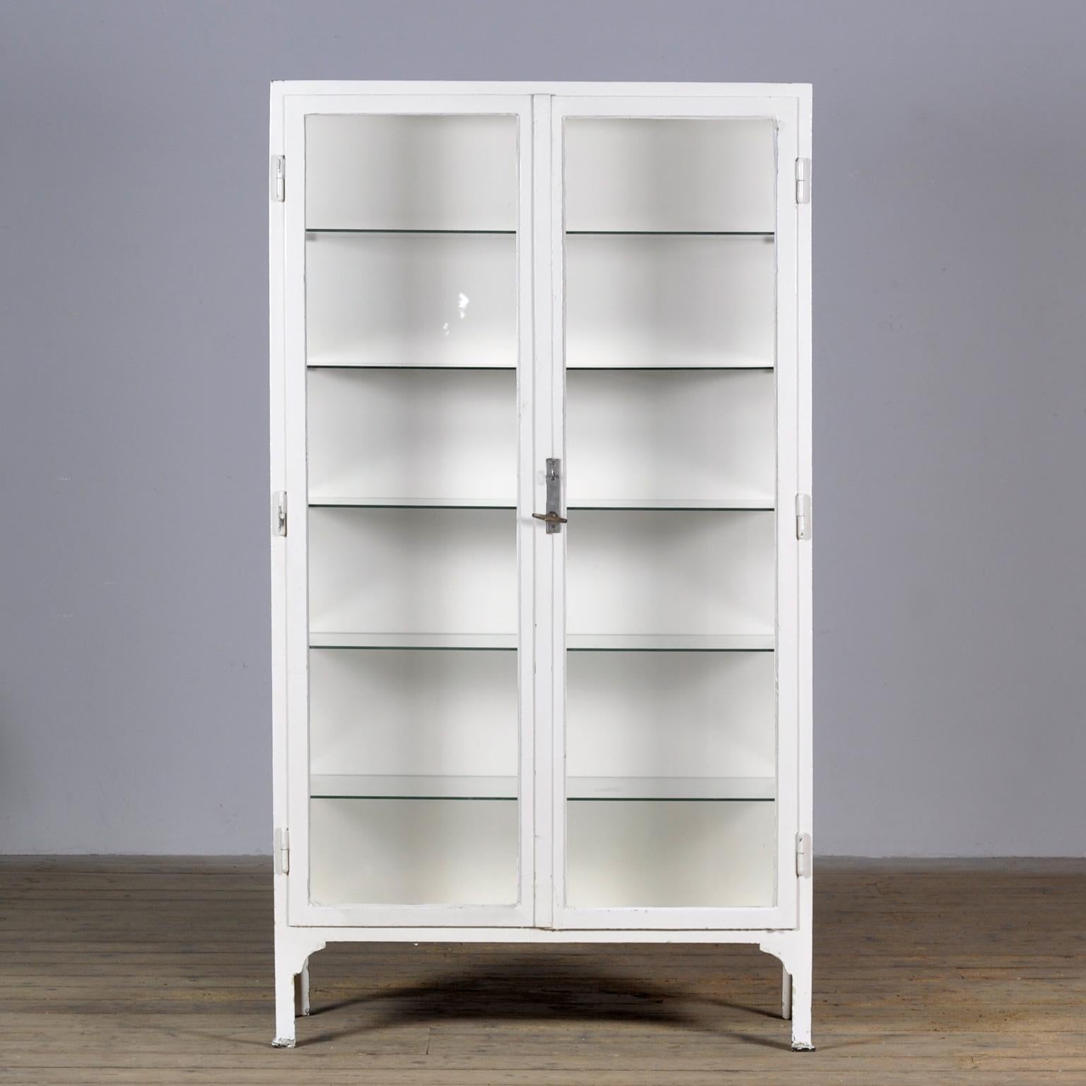 Medical cabinet from the 1930s. The cabinet is produced in Hungary and is made of thick iron and the original antique glass. With 5 glass shelves of 6mm thick. The lock and handle are original and functional.