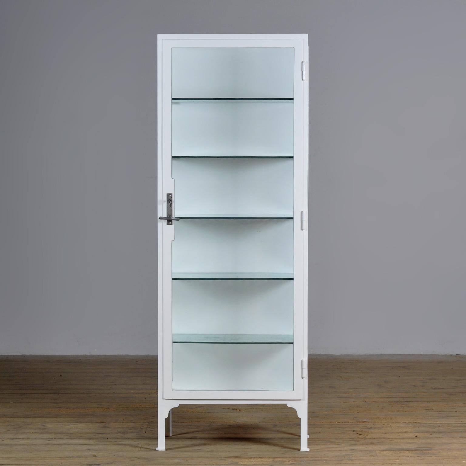 Medical cabinet from the 1930s. The cabinet was produced in Hungary and is made of thick iron glass. The 8mm thick glass shelves are original. The shelves have a green tint due to the lead in the glass. The lock and handle are also original and