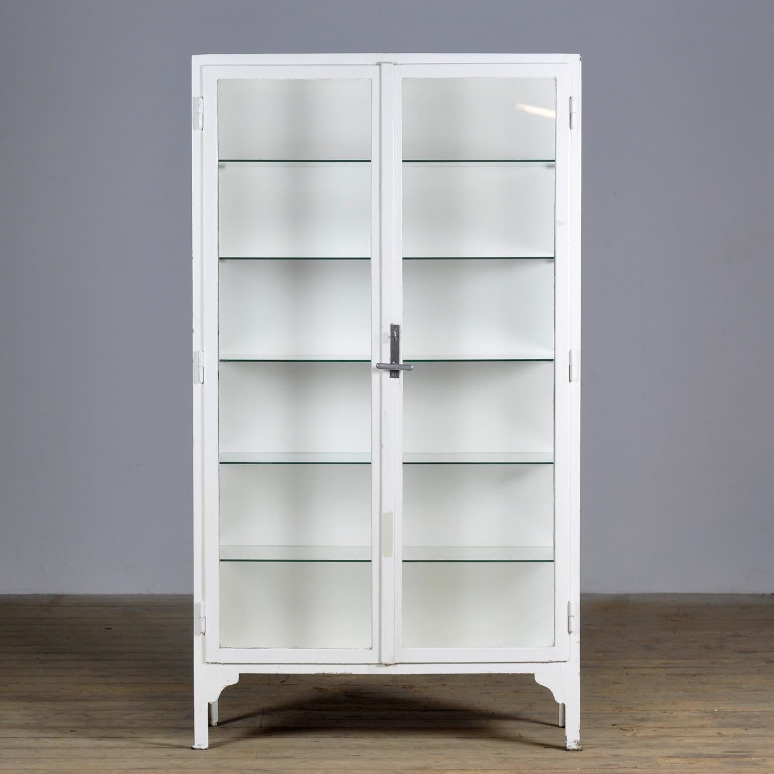 Medical cabinet from the 1930s. The cabinet is produced in Hungary and is made of thick iron and the original antique glass. With 5 glass shelves of 6mm thick. The lock and handle are original and functional.