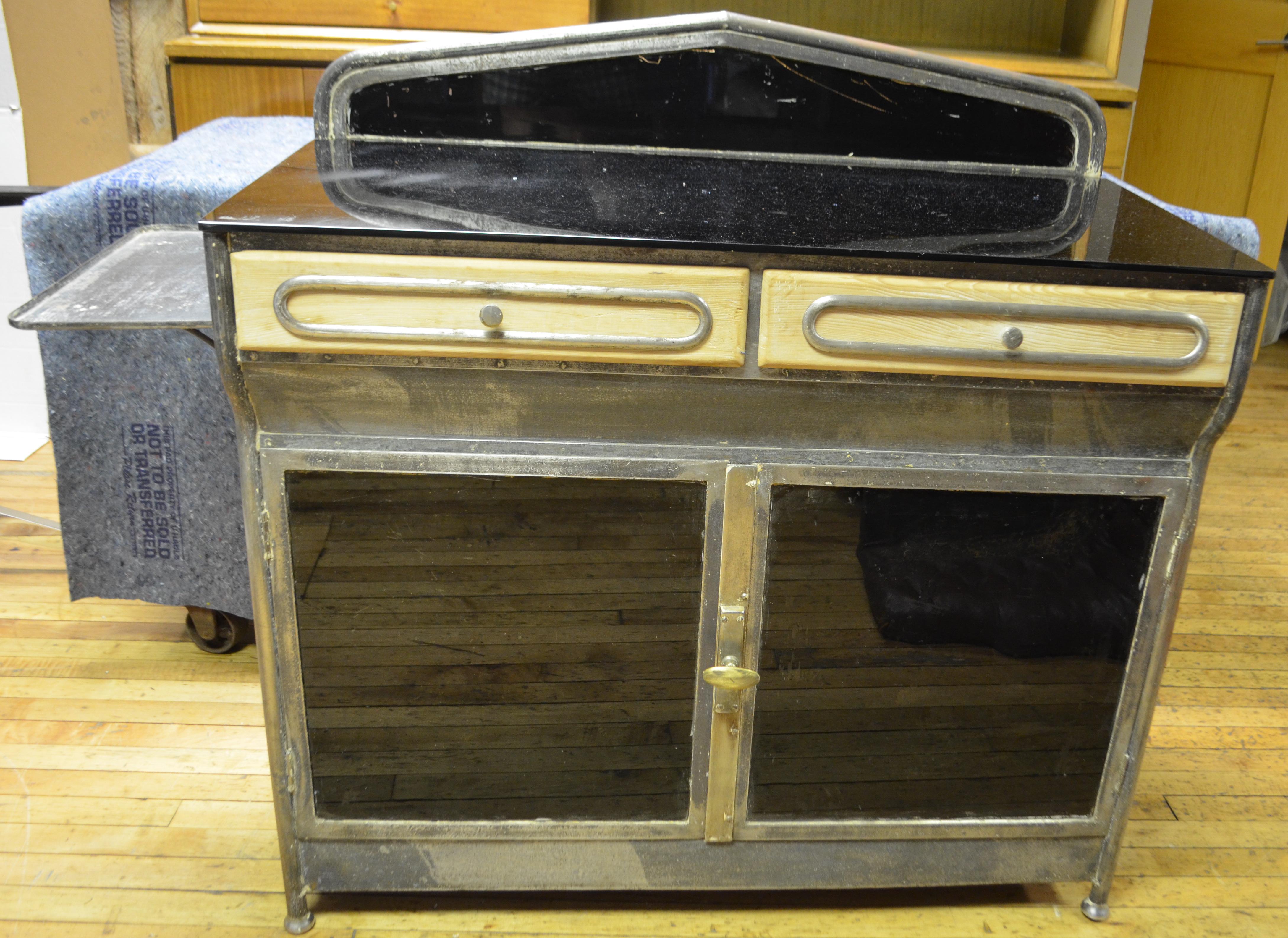 Medical cabinet, Art Deco, circa 1920s. Dark glass mirrors as back splash, counter top and bottom storage doors. Two wooden drawers with steel filagree design and steel shelf on left-hand side. Bottom cabinet offers additional storage. Ideal