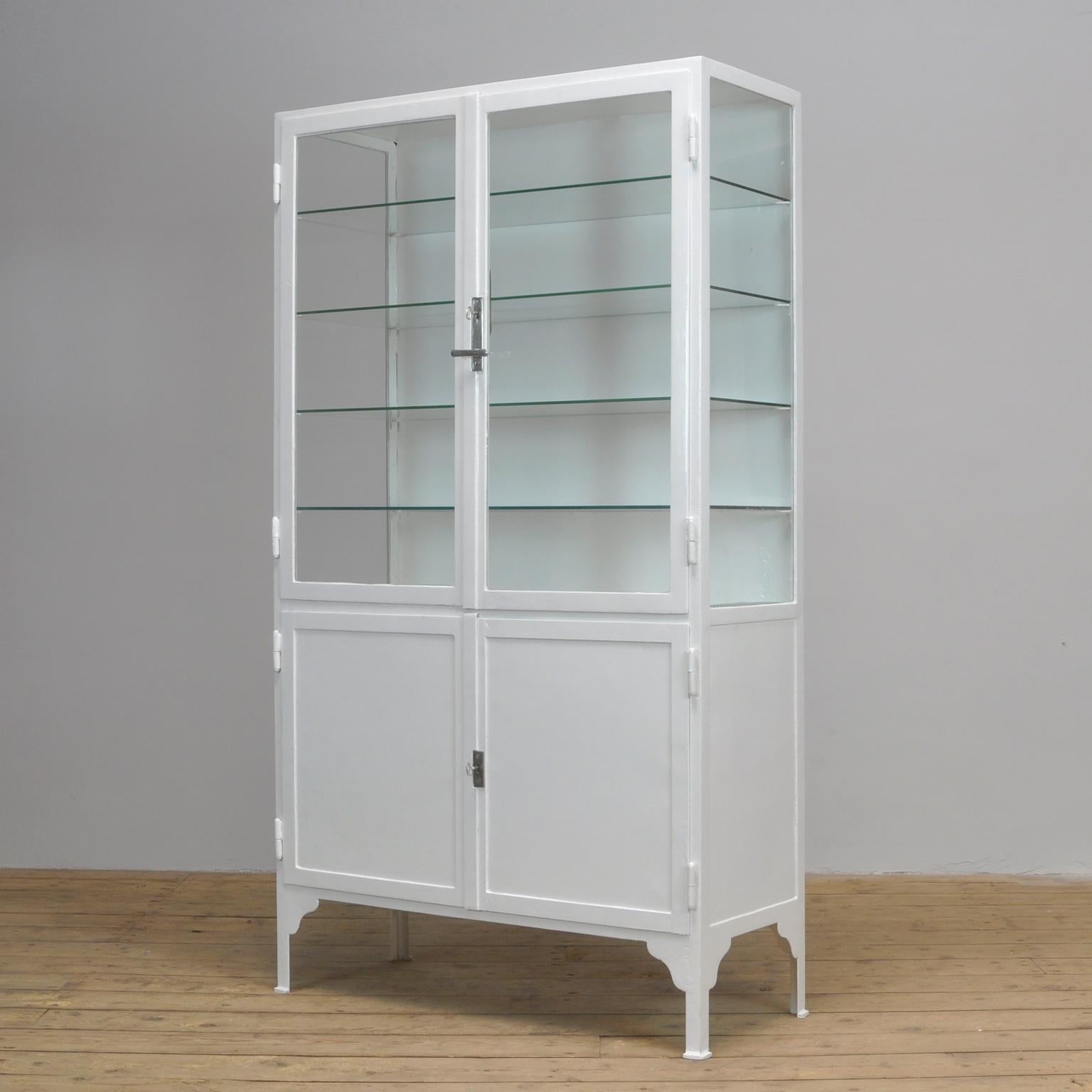 This former medical cabinet was produced in the 1940s in Hungary. It is made of thick iron and antique glass. In the upper part, there are four new glass shelves. The original locks are in perfect working condition.
The cabinet has been repainted